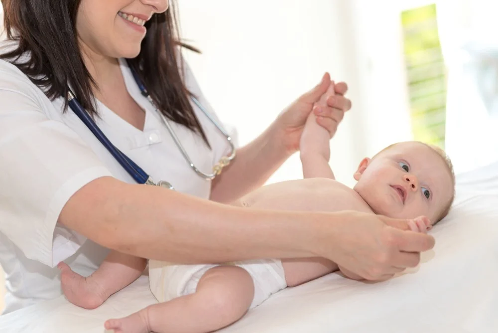 Healthcare professional examining an infant during a pediatric visit, representing the importance of early diagnosis and genetic testing for children.