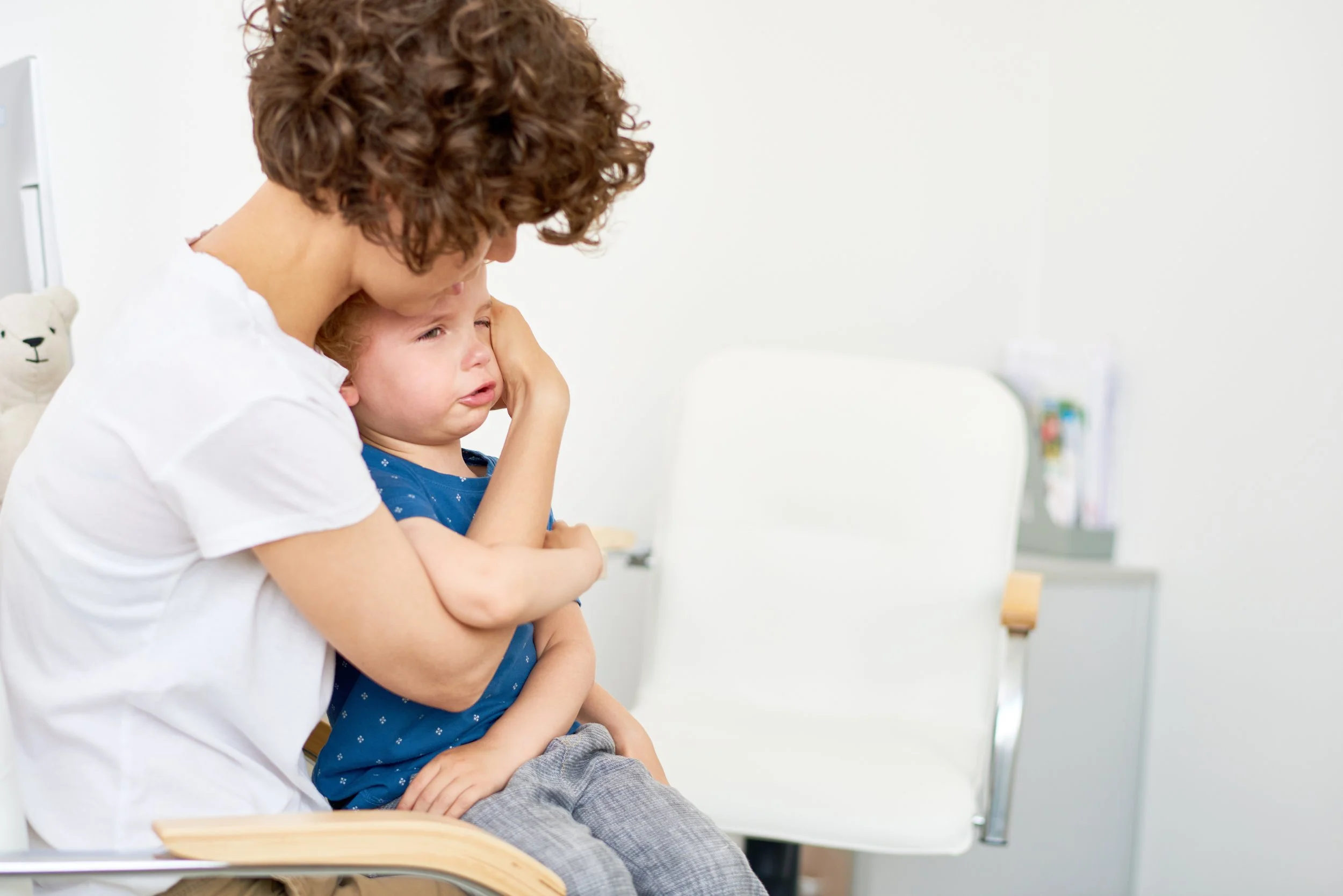Parent comforting a child during a medical visit, representing family support throughout the diagnostic journey.