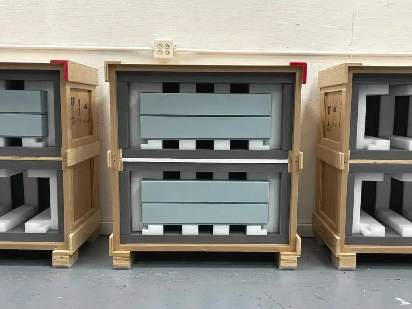Row of empty shipping crates with foam padding, stacked on wooden pallets in a warehouse.
