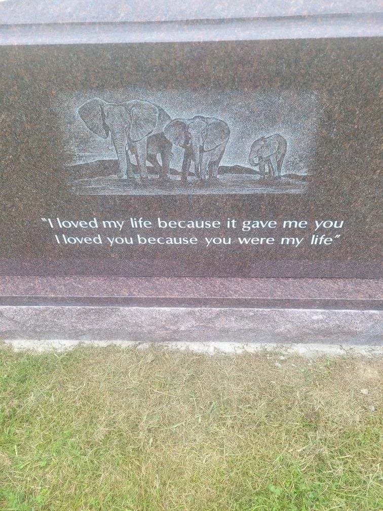 A stone memorial with an engraving of four elephants and an emotional quote.