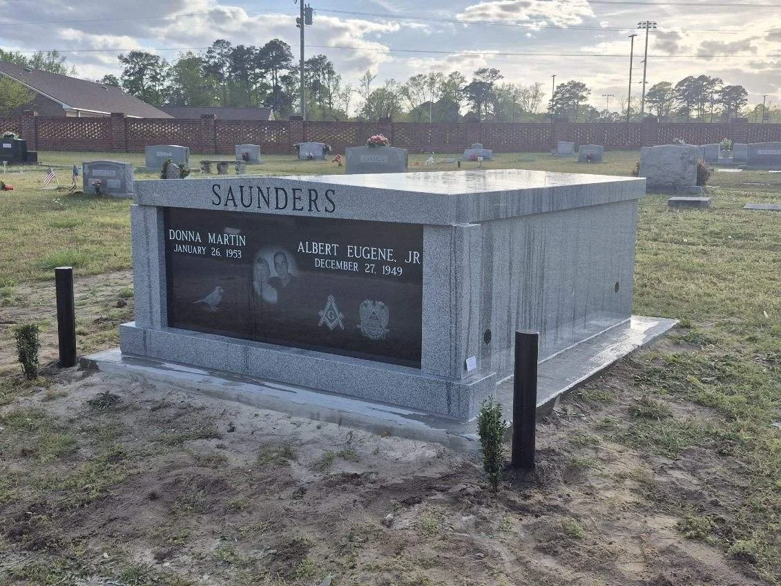 Gravestone in a cemetery for Donna Martin and Albert Eugene Jr. with their birth and death dates, granite monument, and surrounding small bushes.