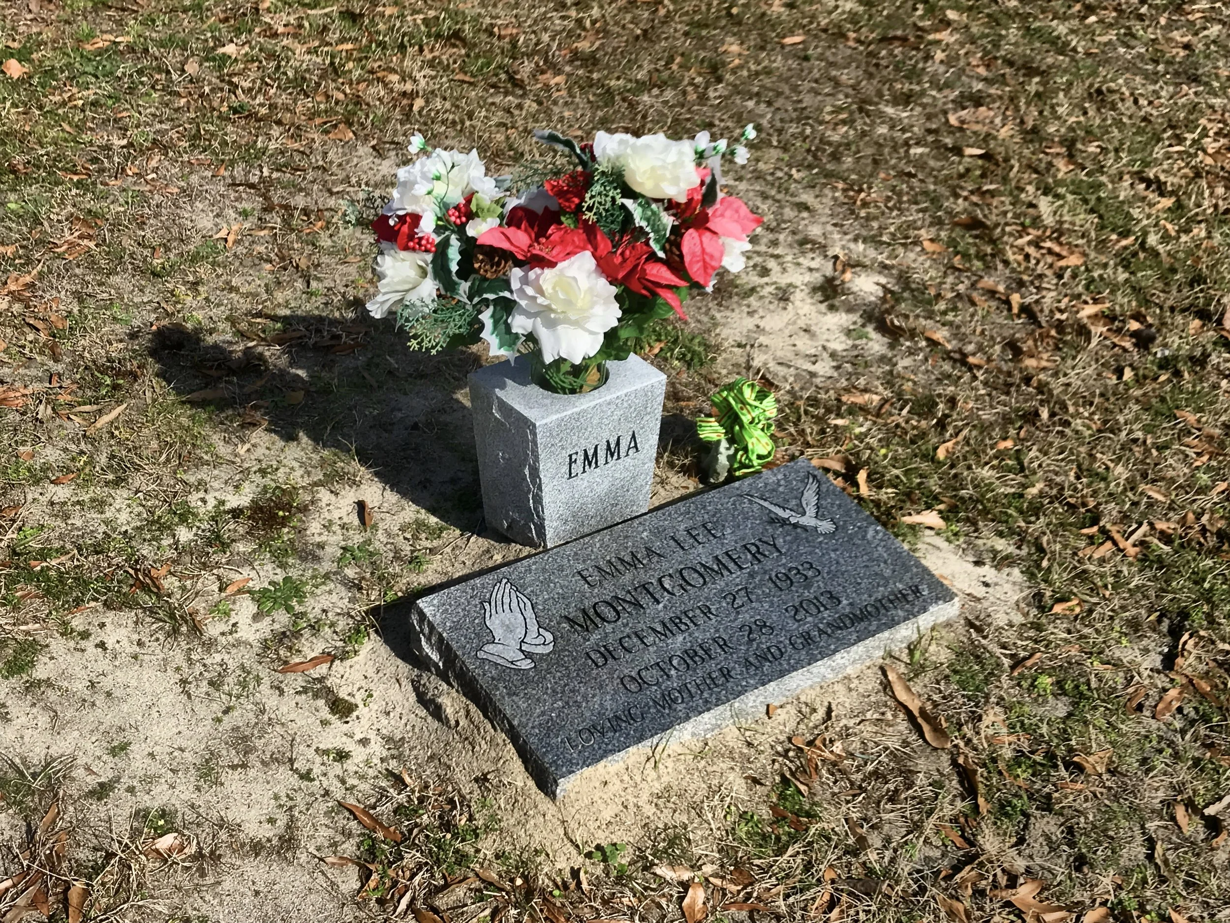 Gravestone with flowers placed on it. The gravestone is marked with the name EMMA and the words 'LOVING MOTHER AND GRANDMOTHER'.