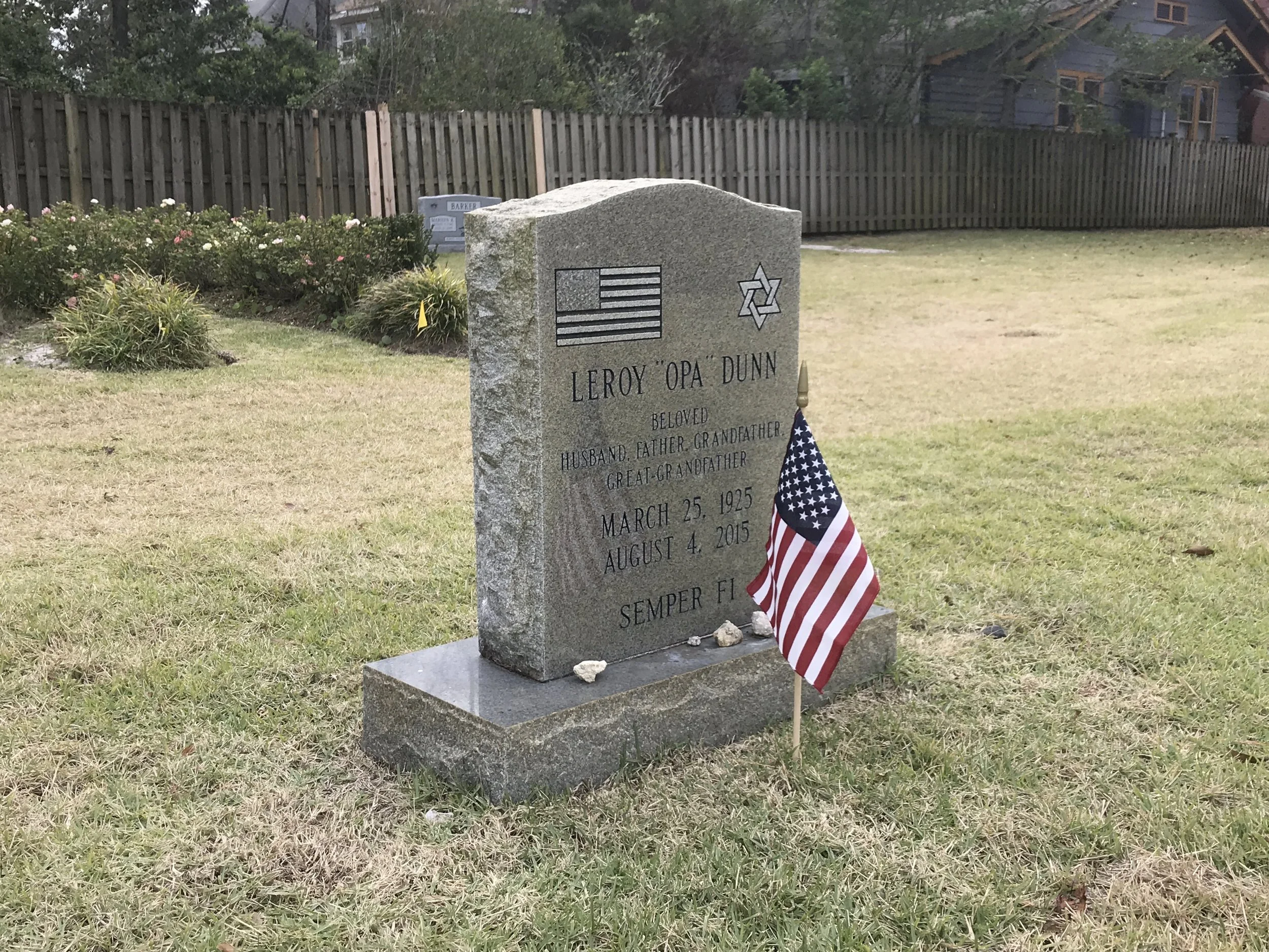 Tombstone for an American Veteran, decorated with an American flag and a Jewish Star of David, located in a grassy cemetery.