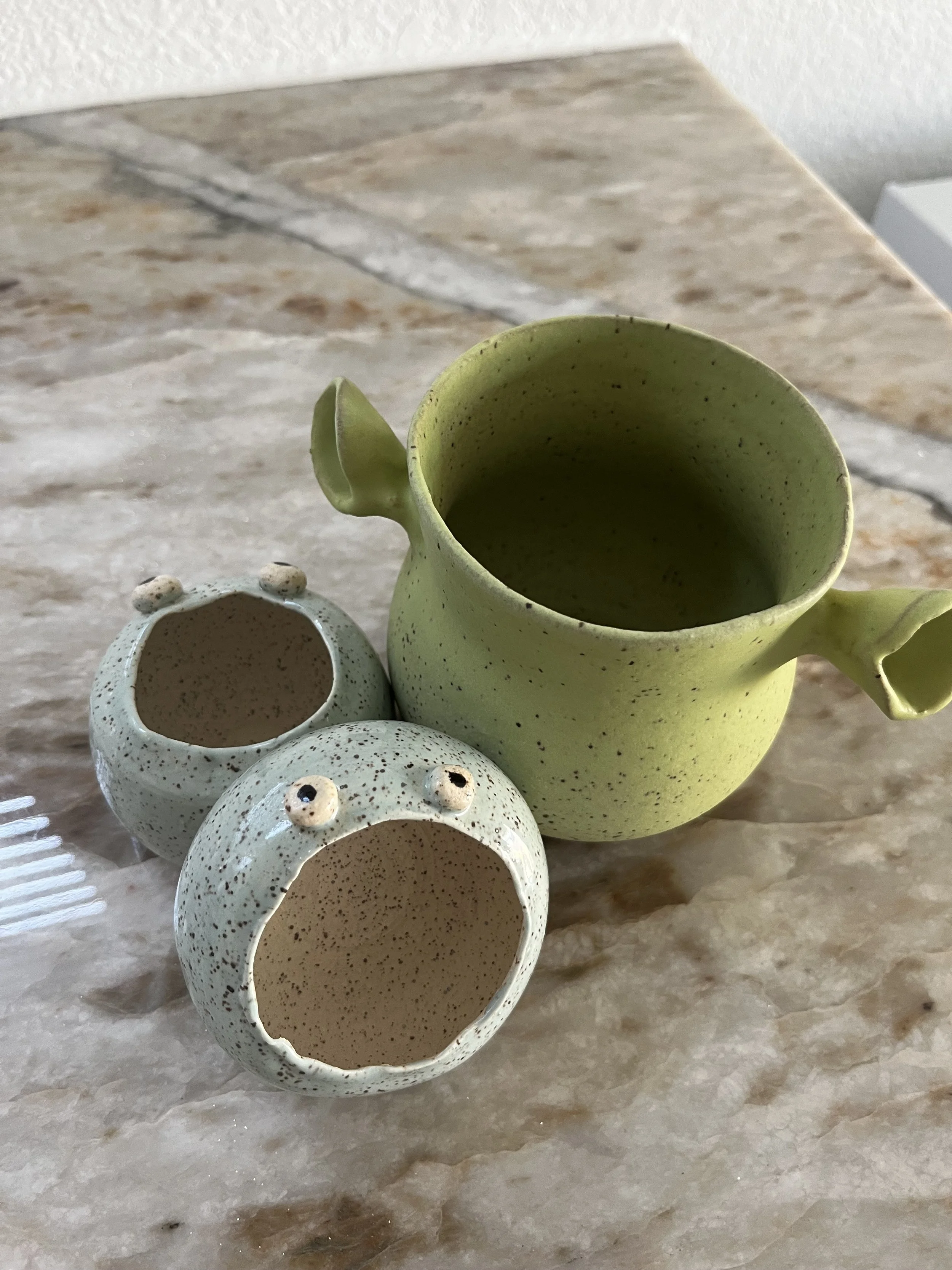 Three ceramic decorative vases with small holes and rounded shapes, placed on a marble surface.