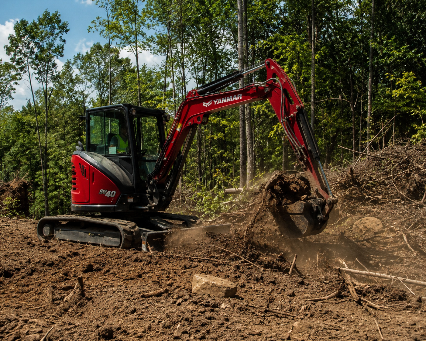 A red Yanmar mini excavator with a black cab is digging soil in a forested area with green trees and a partly cloudy sky in the background.