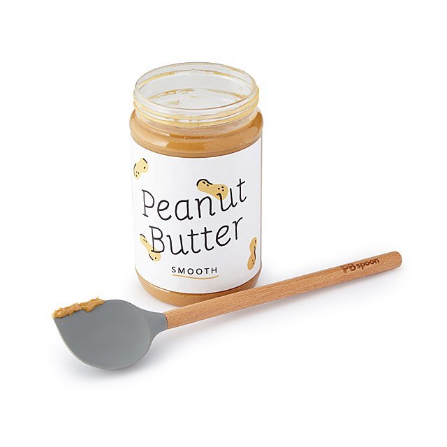 Open jar of peanut butter with a label reading "Peanut Butter Smooth" and a wooden spoon with peanut butter on it in front of the jar.