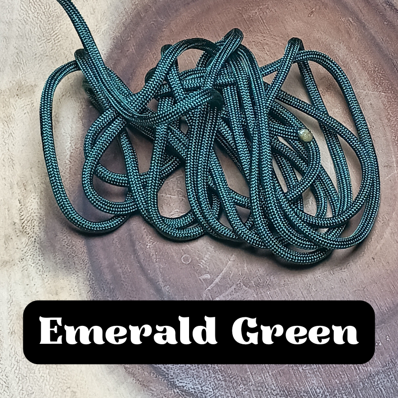 A tangled green and black rope on a wooden surface with a label that says 'Emerald Green'.