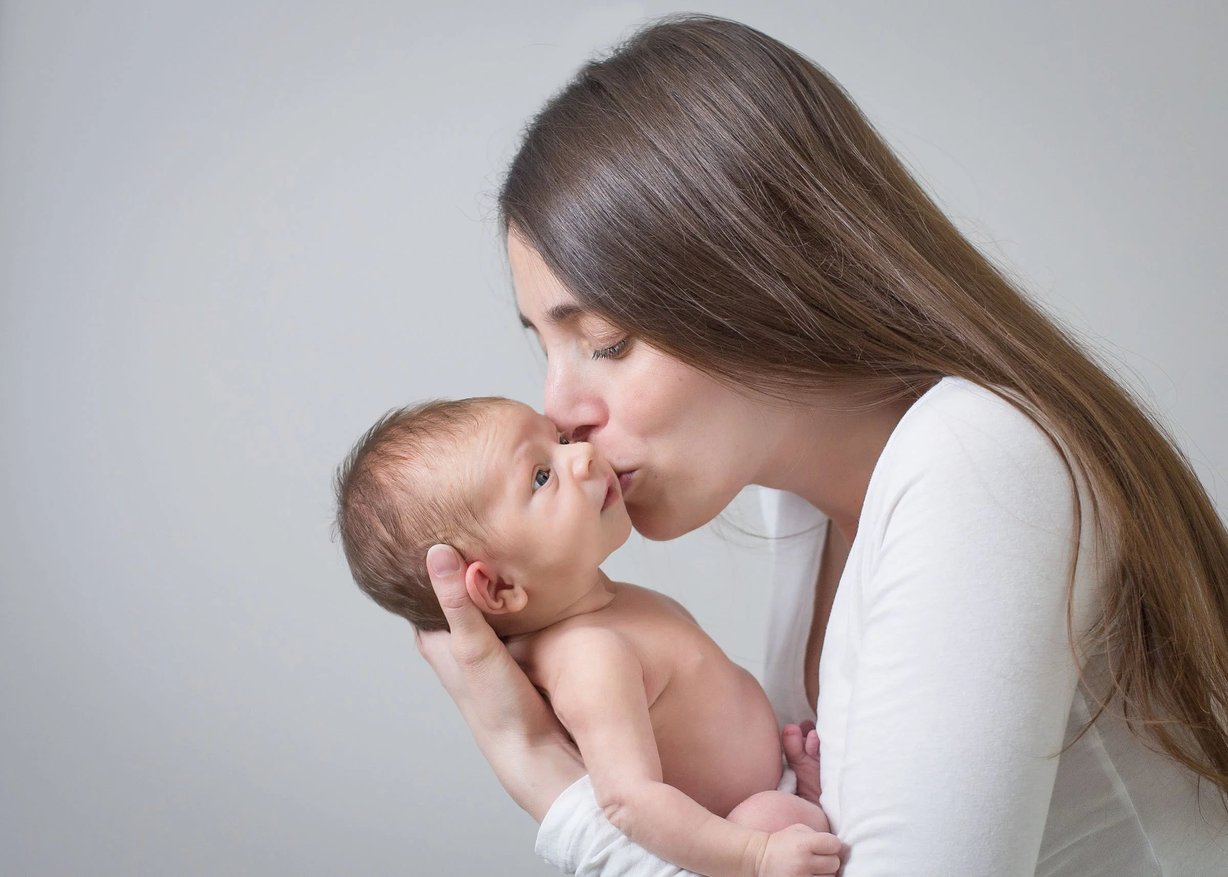 Mother holding her newborn baby during a posed newborn photography session in Bromley by Kate See Photography.