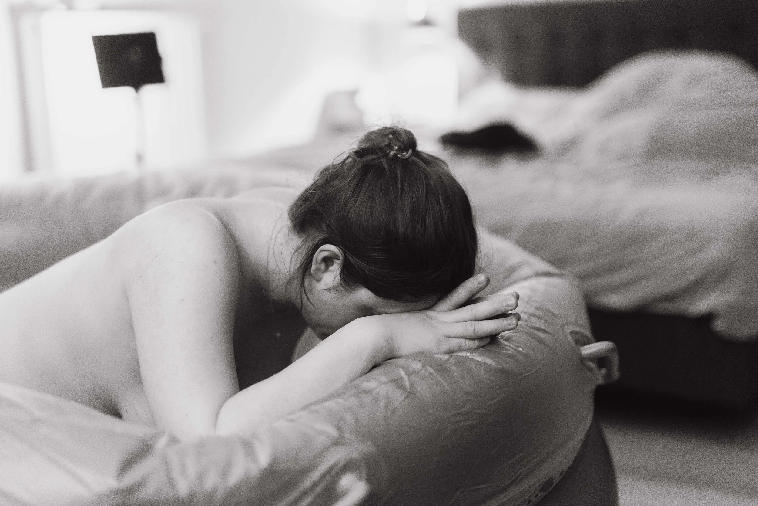 A person lying face down on a bed, resting their head on their crossed arms.