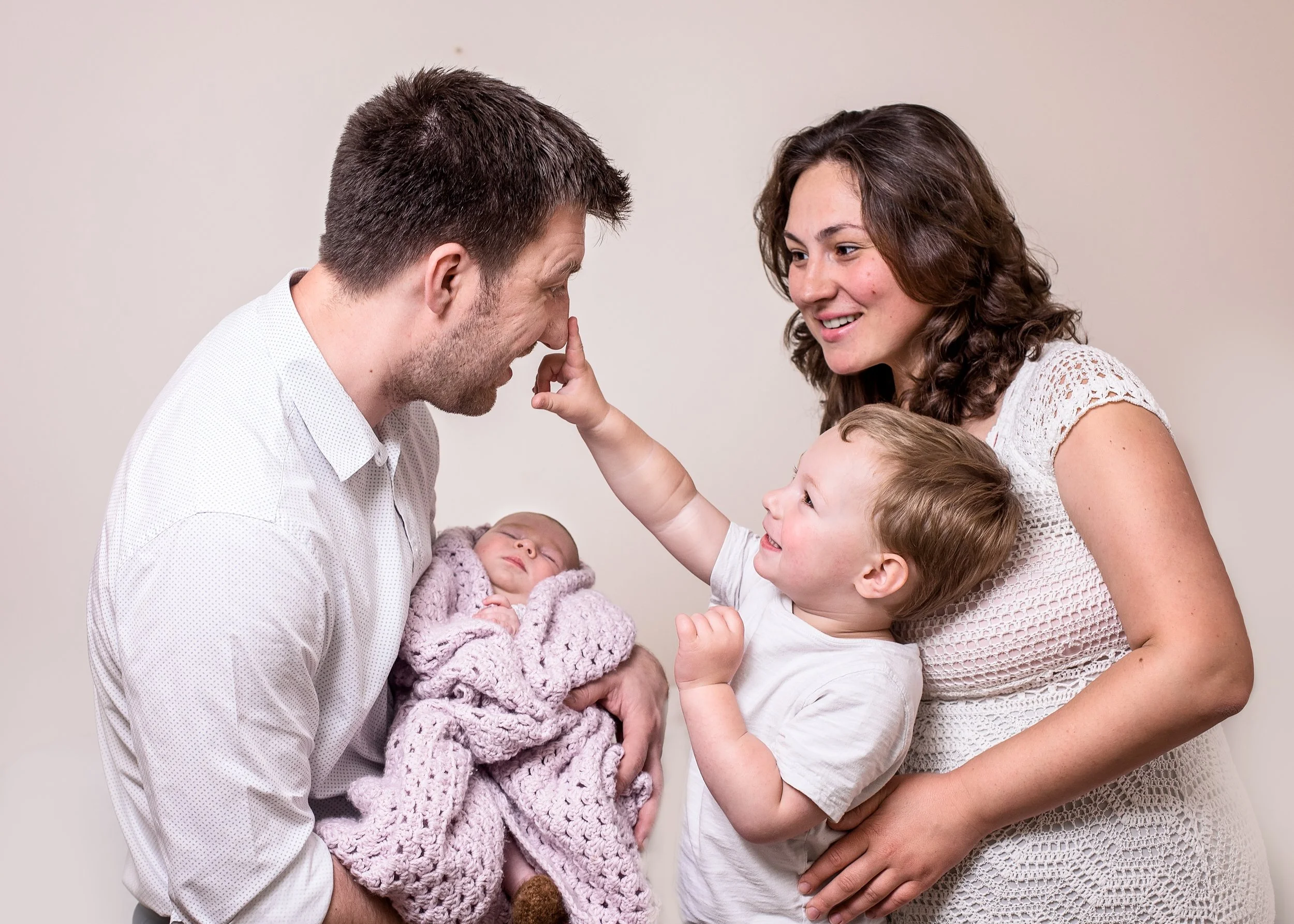 New parents tenderly holding their newborn baby together during an at-home family newborn session in South East London by Kate See.