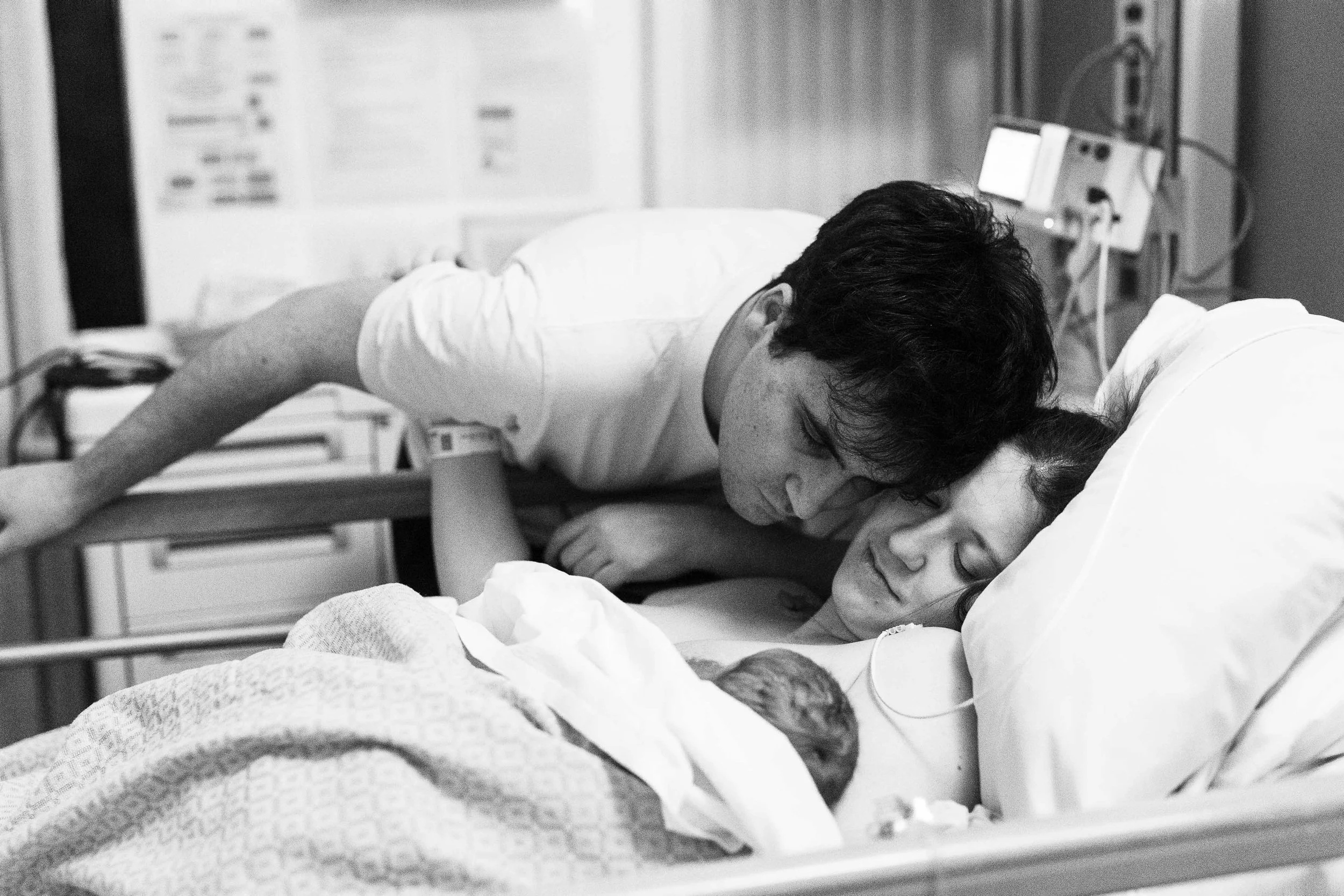 A woman and a child lying on a hospital bed, hugging each other.