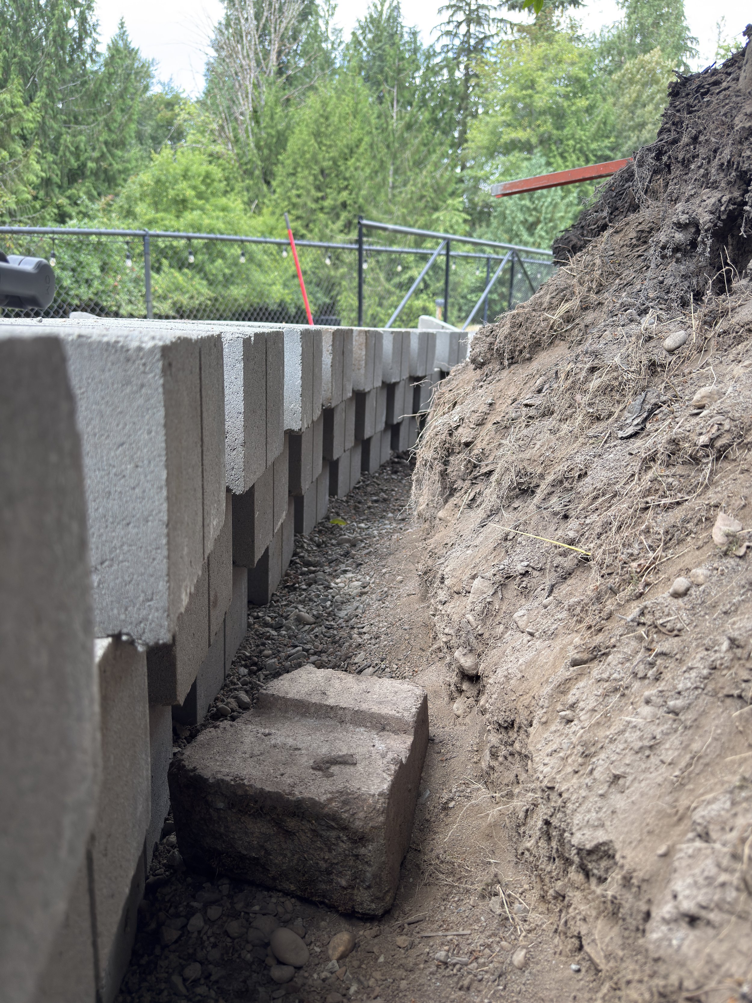 Drain rock and gravel backfill behind a retaining wall showing proper drainage installation