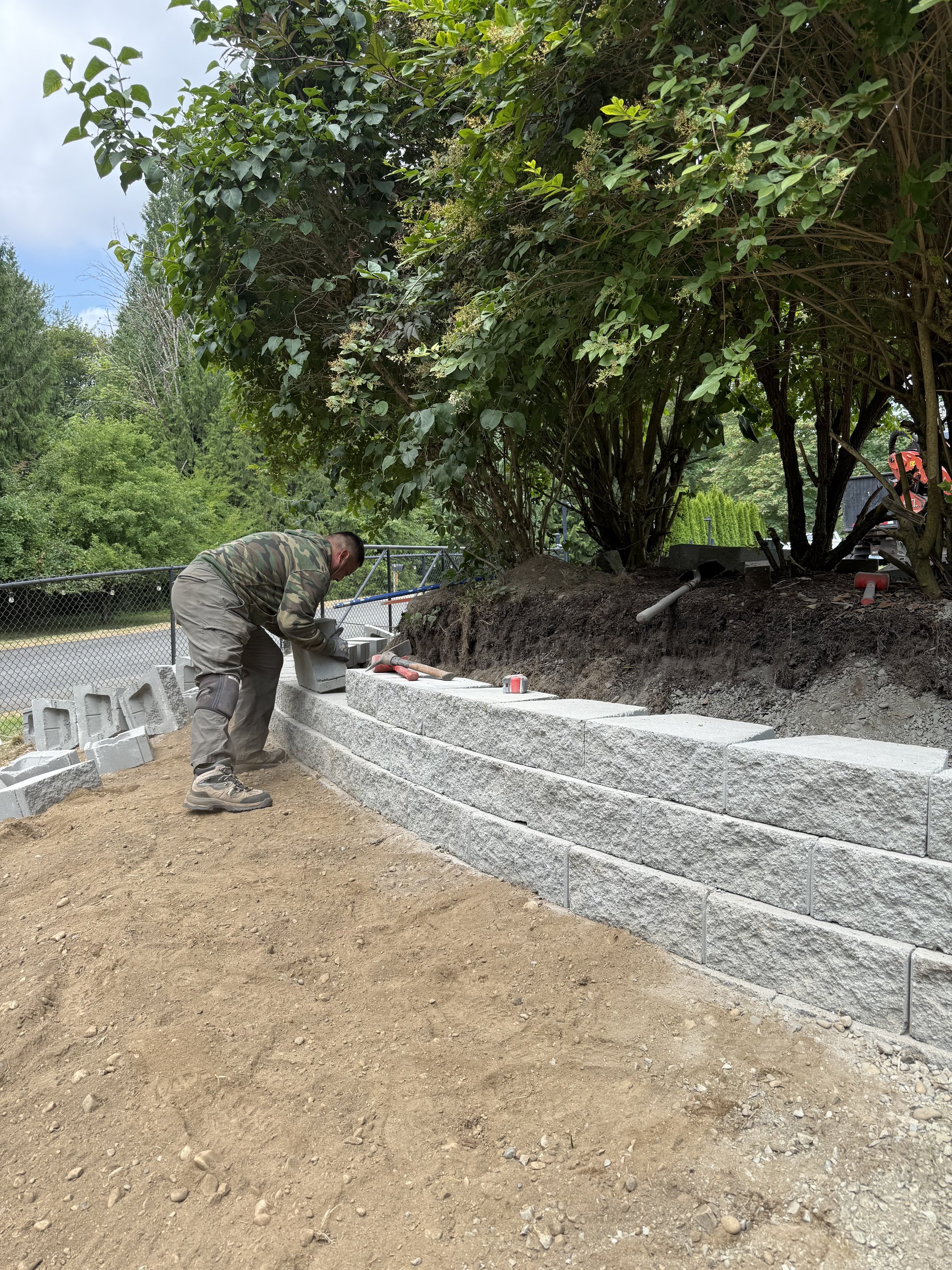 Finished section of a concrete block retaining wall built to stabilize a sloped property in Washington