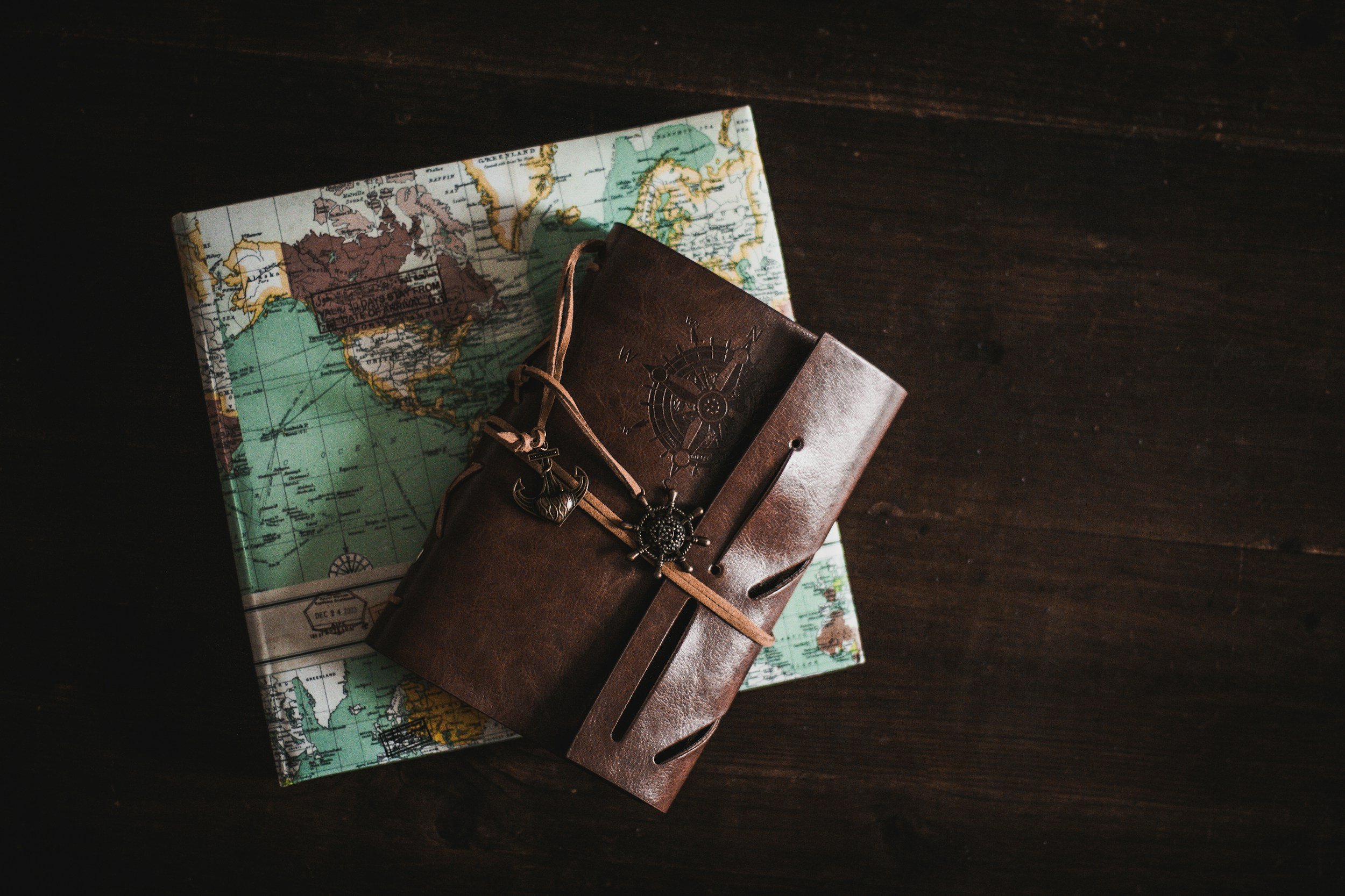 Journal with an anchor ornament, and a keychain placed over a folded map.