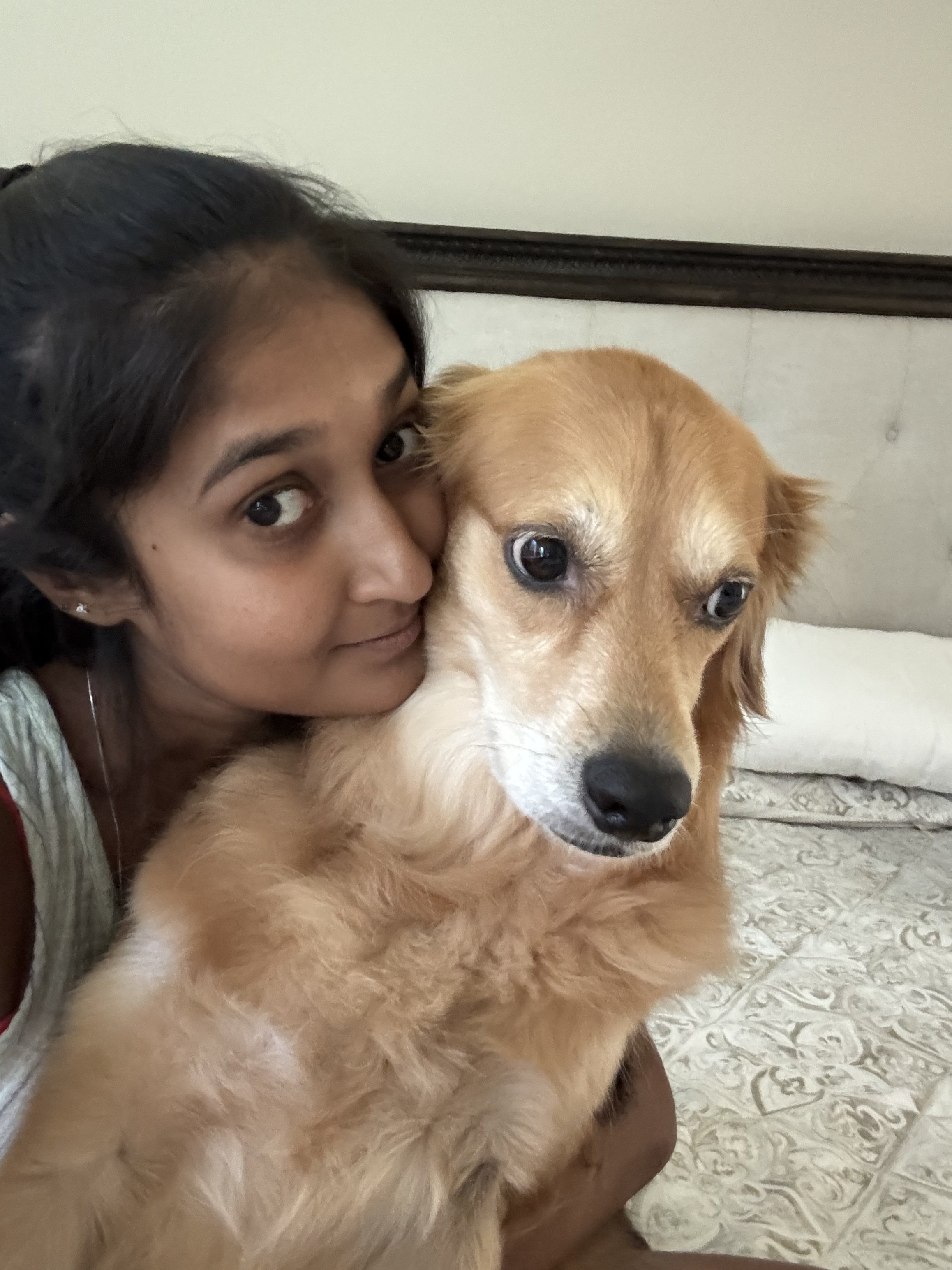 A person and a golden retriever dog close together indoors, with the person resting their face near the dog's head.
