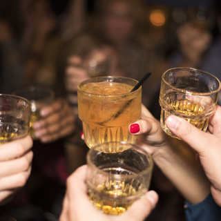 Pessoas brindando com taças de drink em ambiente social
