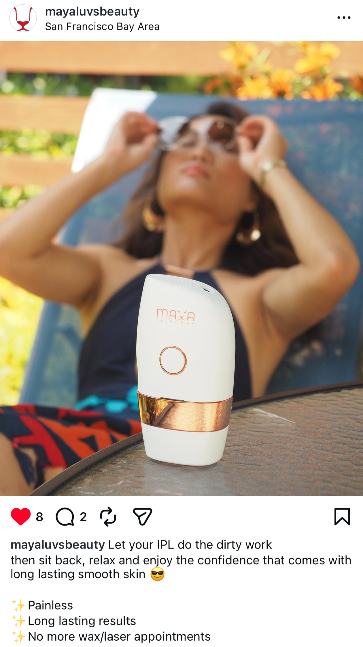 A woman relaxing on a lounge chair outdoors, wearing sunglasses, with a skincare device labeled "MAYA" in the foreground, and flowers in the background.