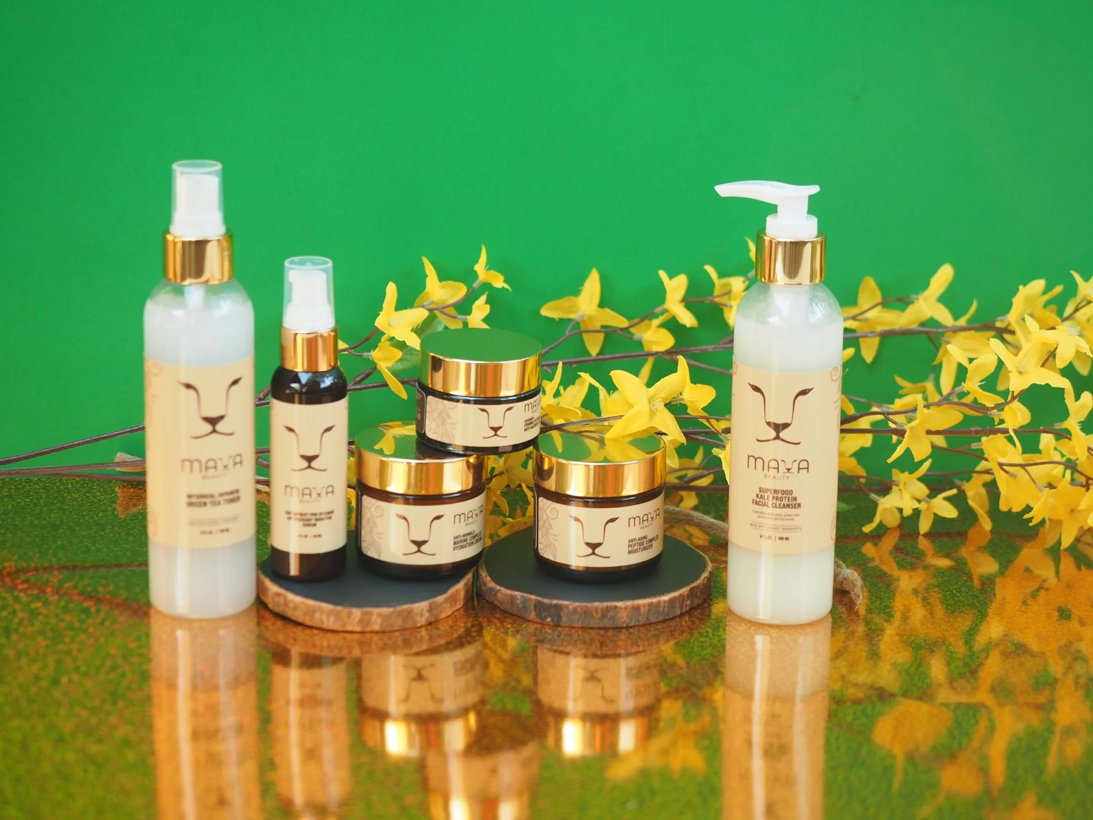 A display of skincare products with a lion's face logo, set against a green background with yellow flowers and a reflective surface.