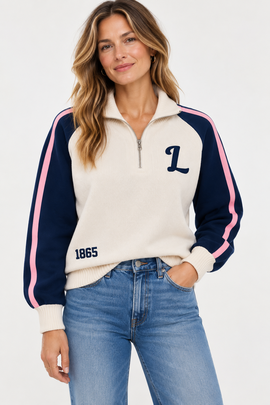 Woman modeling a cream quarter-zip pullover with navy sleeves, pink stripes, and blue jeans