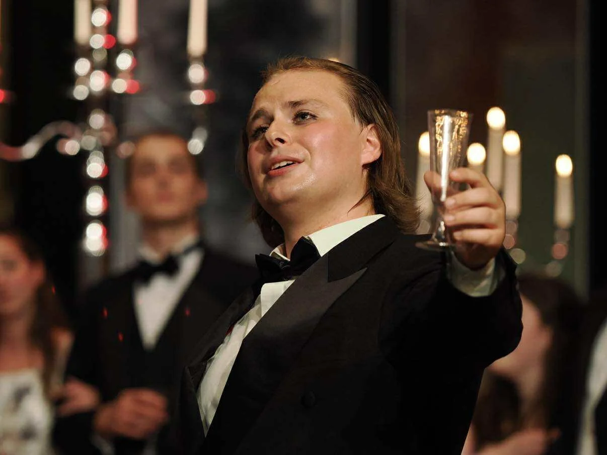 Man in tuxedo raising a champagne glass at a celebration or party.