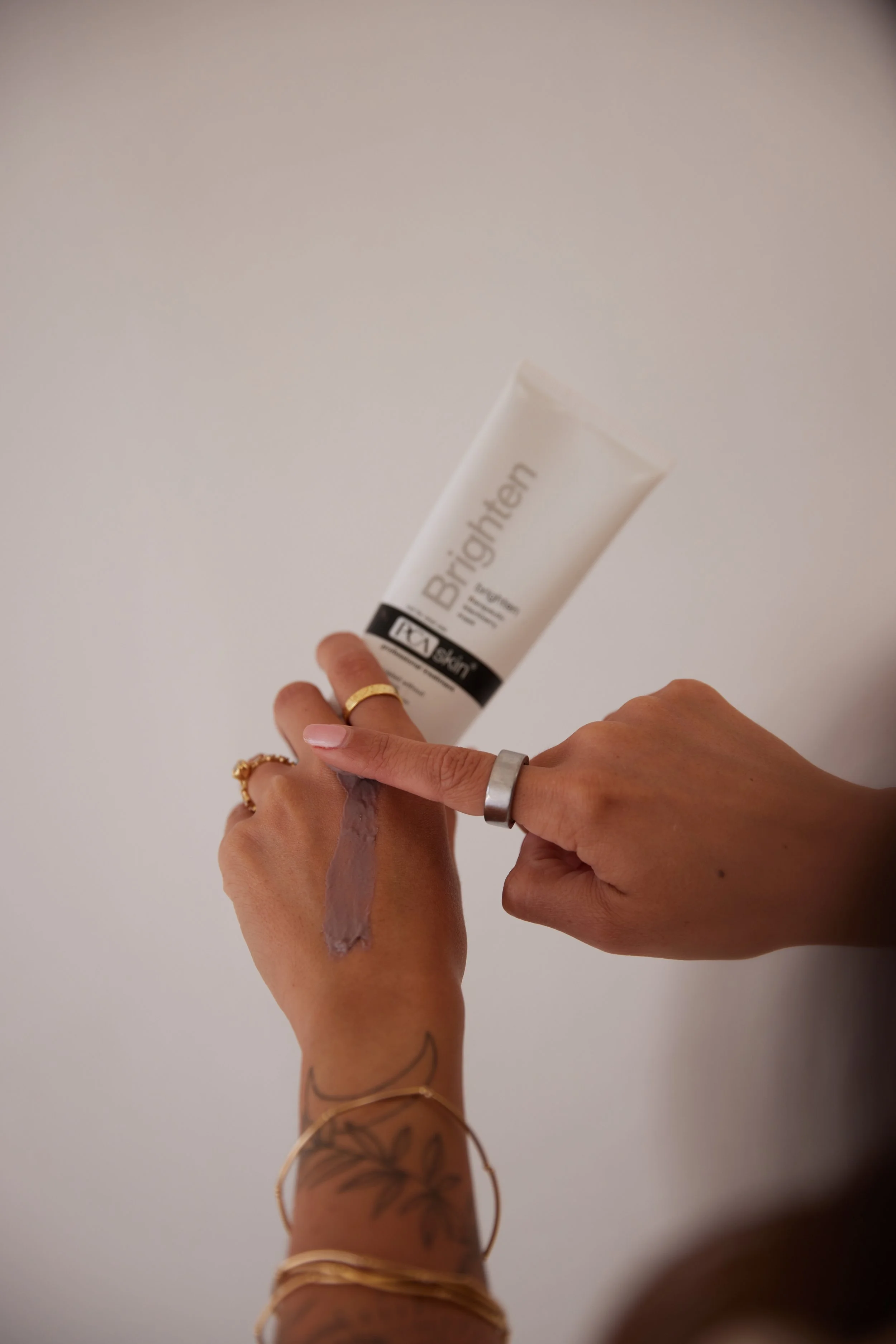 Person applying moisturizer from a tube labeled 'Brighten' onto their wrist.