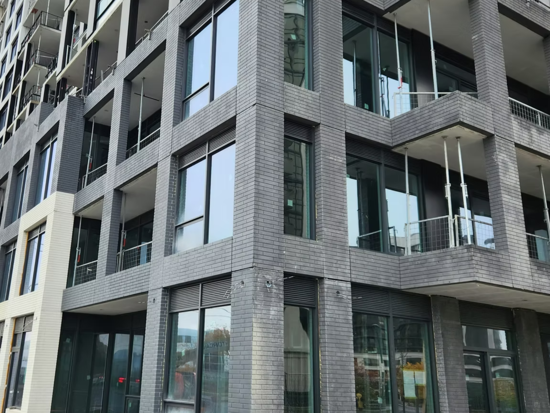 A modern multi-story building with brick exterior and large glass windows and balconies.