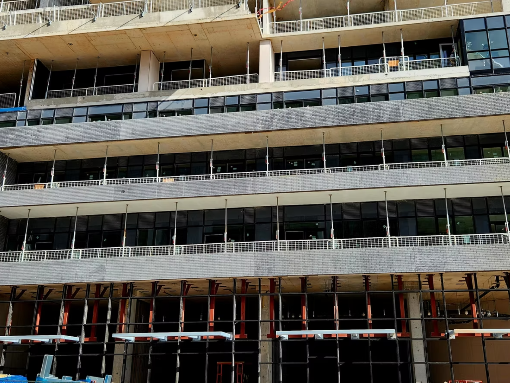 Construction site of a multi-story building with glass windows, concrete floors, and scaffolding, showing an in-progress high-rise structure.