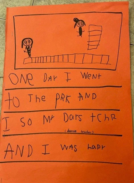 Childish drawing on orange paper depicting two stick figures, one on the ground and another jumping. Handwritten text reads: "One day I went to the park and I so Mr Dars Teacher and I was happy."