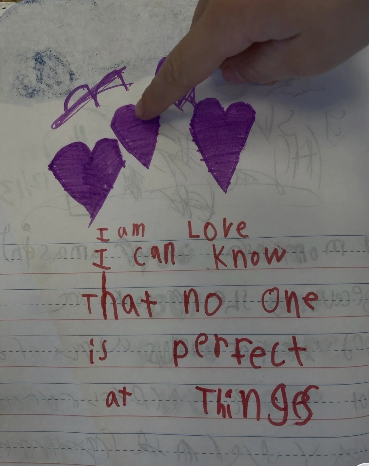 A piece of paper with three purple hearts drawn at the top and a handwritten message in red ink that says, 'I am Love, I can know, That no one is perfect.'