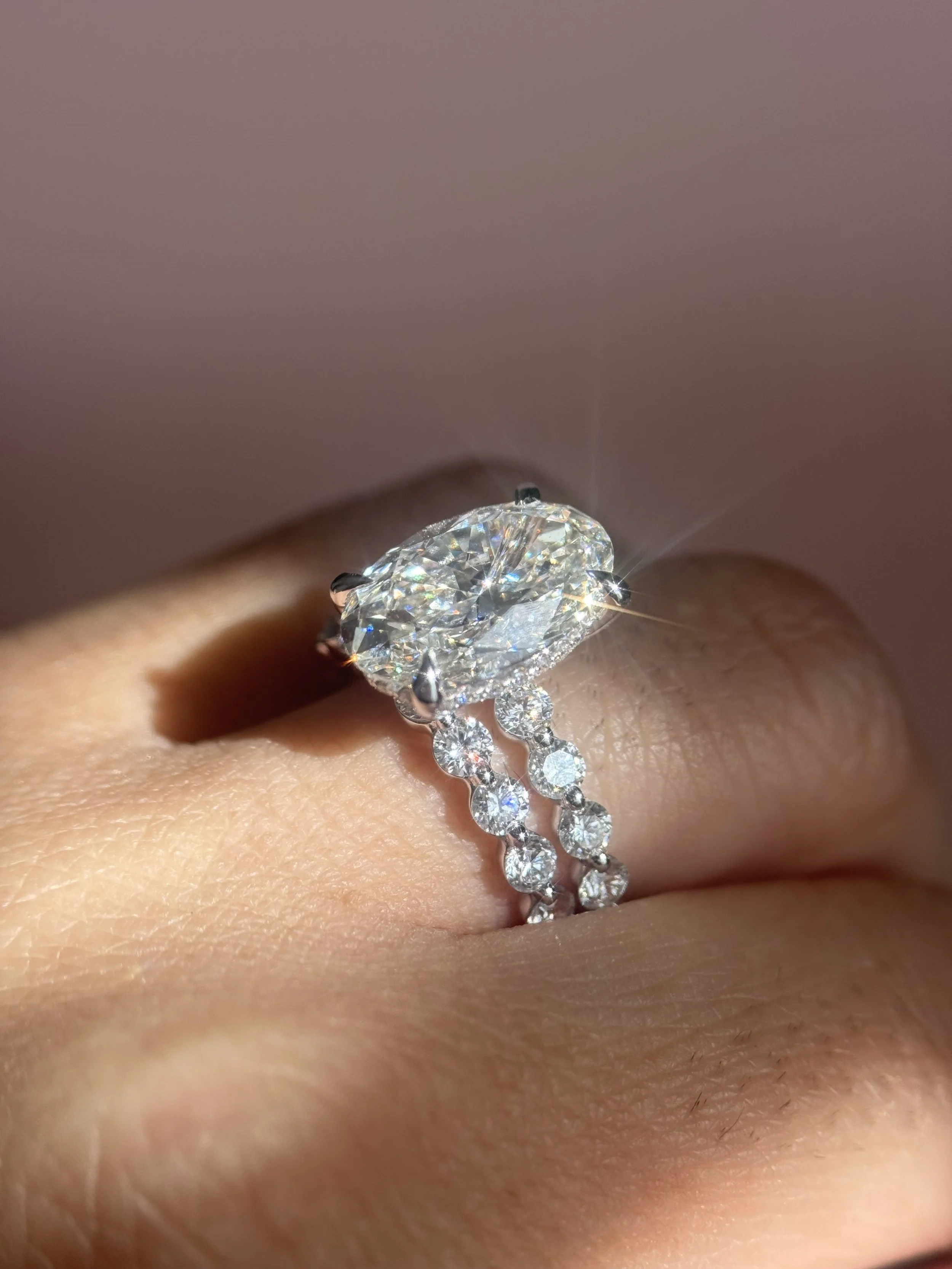 Close-up of a diamond engagement ring on a person's finger, featuring a large central diamond and a diamond-studded band.