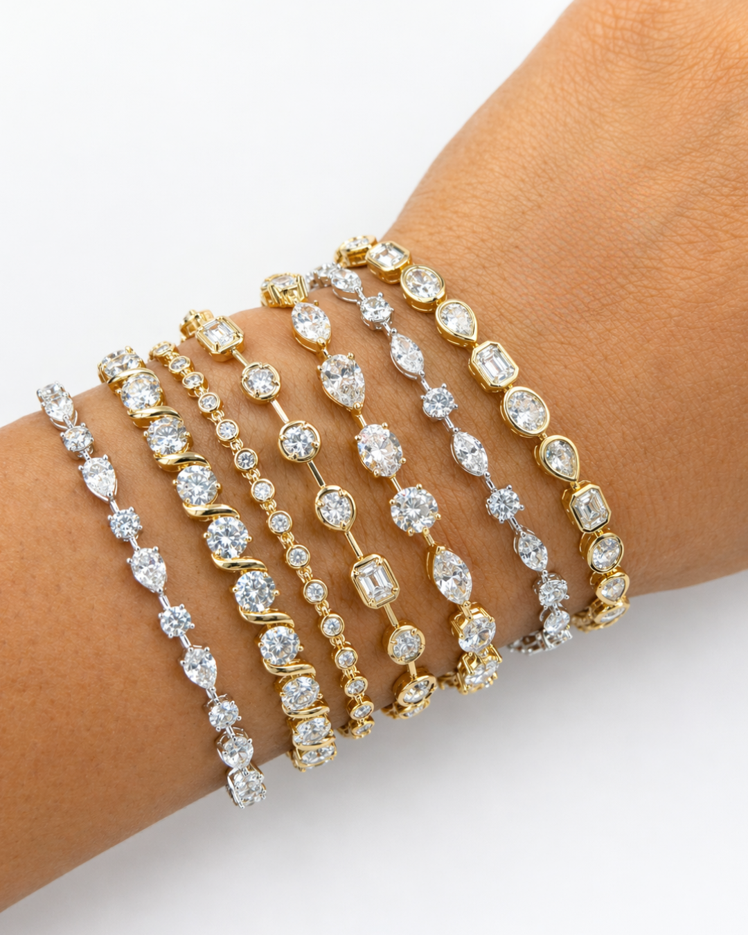 Multiple gold and silver bracelets with clear sparkling gemstones on a person's wrist