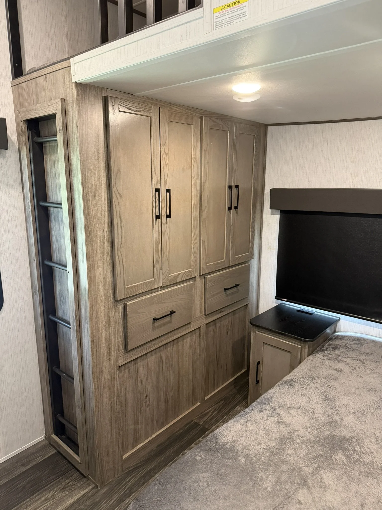 Interior of a room with wooden cabinets, a TV, and a small table, with a carpeted floor and some overhead lighting.