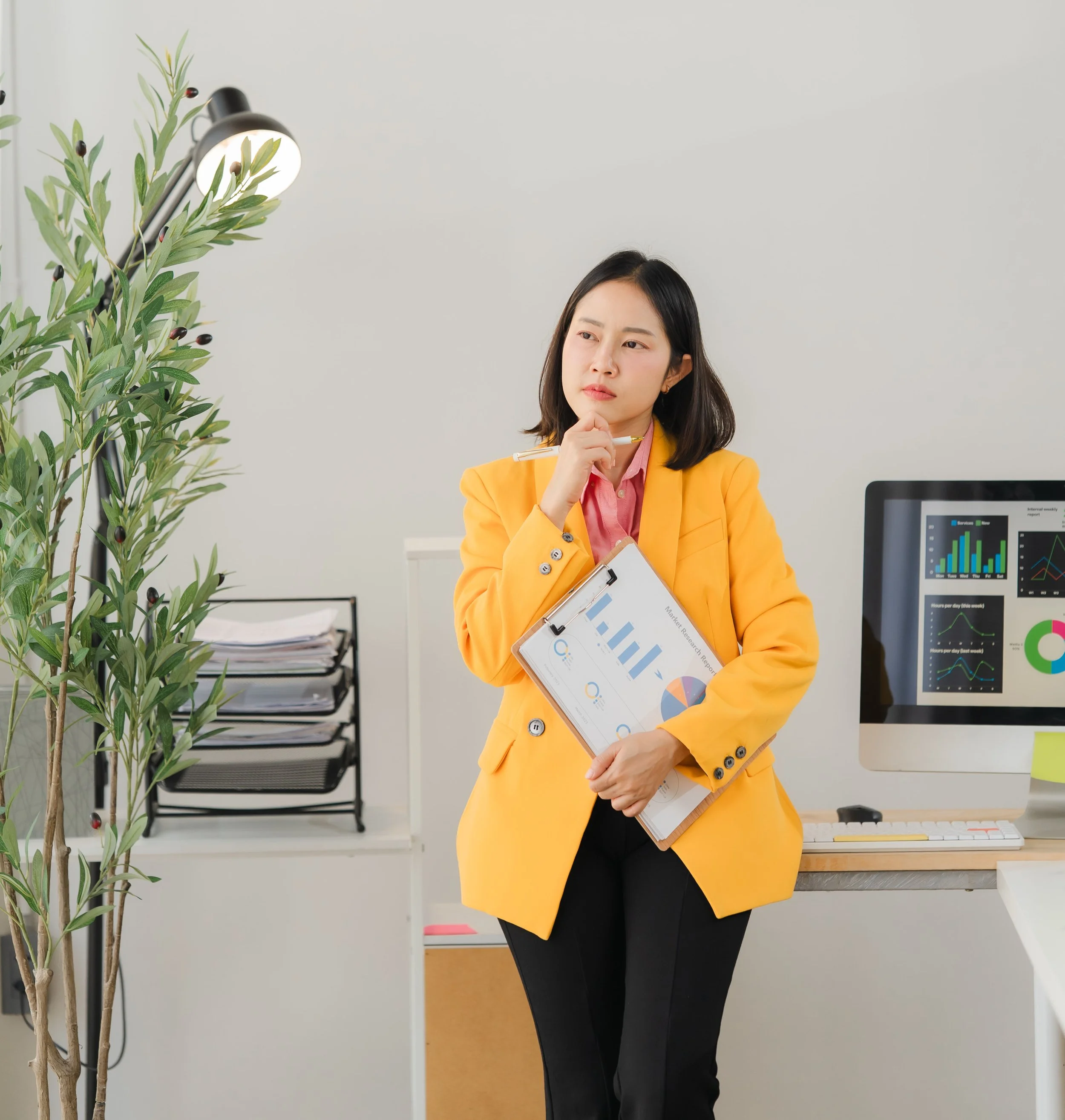 Woman standing with a clipboard in one hand and the other under her chin looking at the 10 reasons