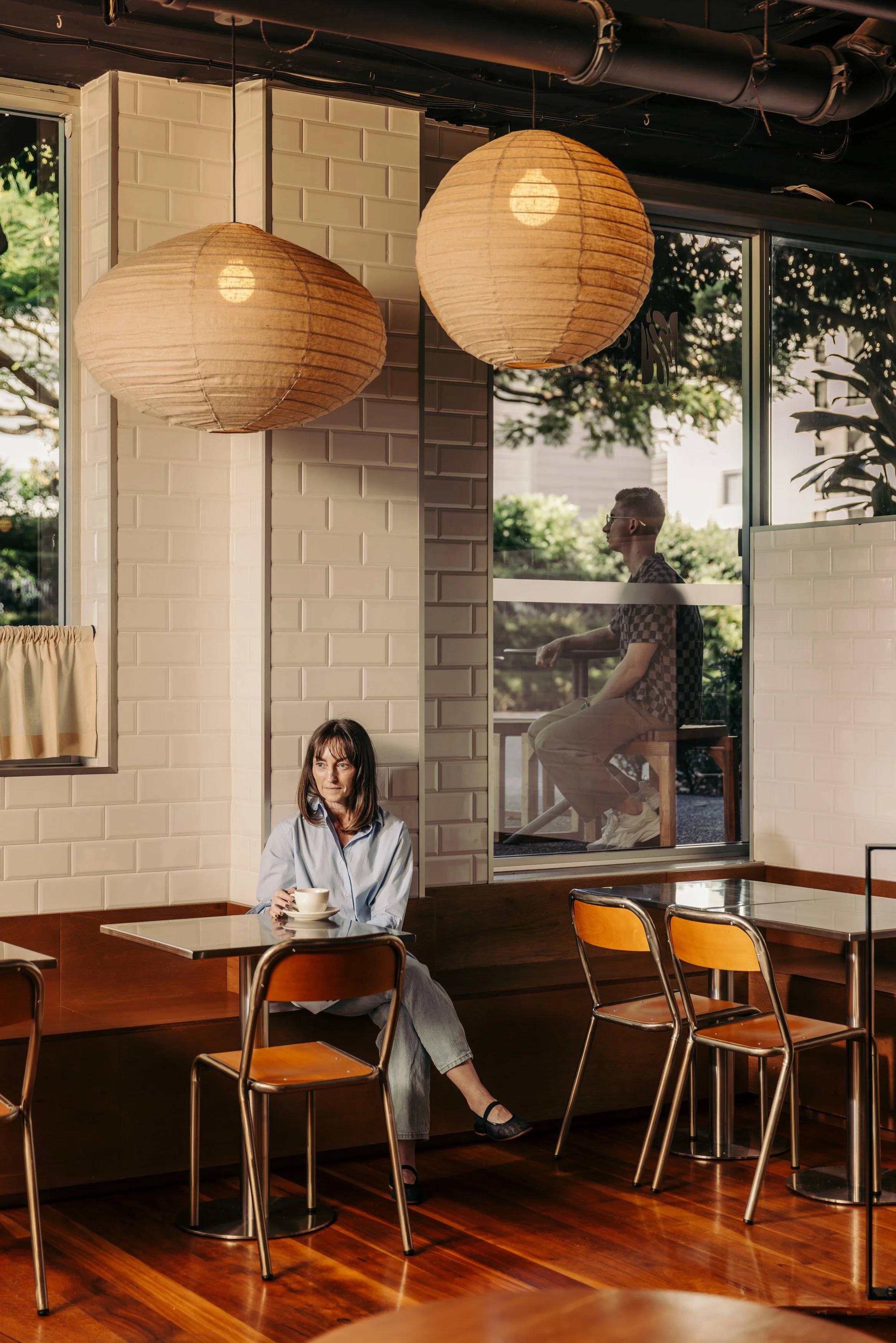 Interior of Kin cafe in Brisbane with paper lantern lighting. The large windows reveal outdoor seating.