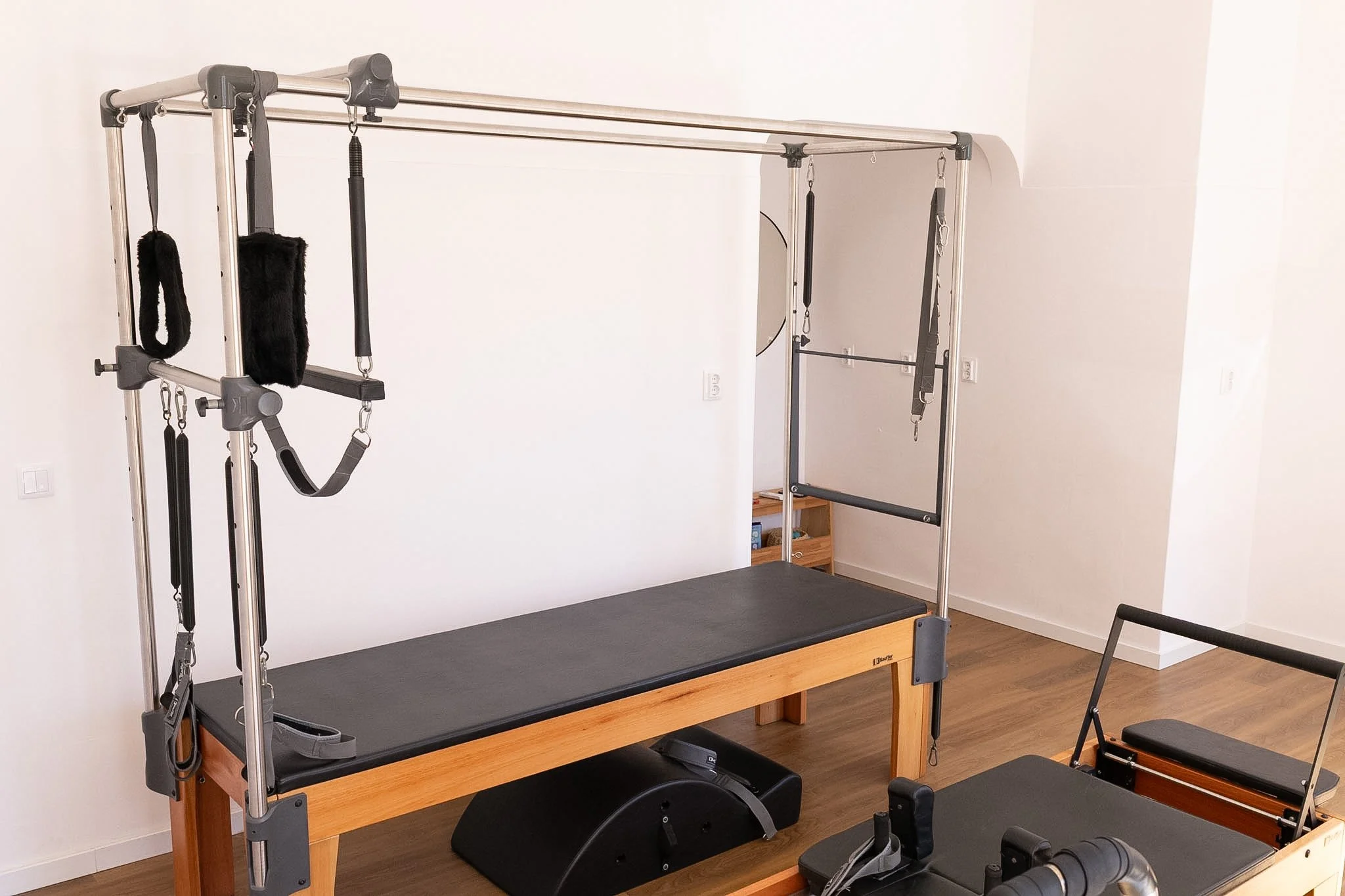 Equipamentos de fisioterapia, incluindo uma mesa de tratamento, plataformas de equilíbrio, faixas elásticas e outros acessórios, em um ambiente de clínica ou consultório.