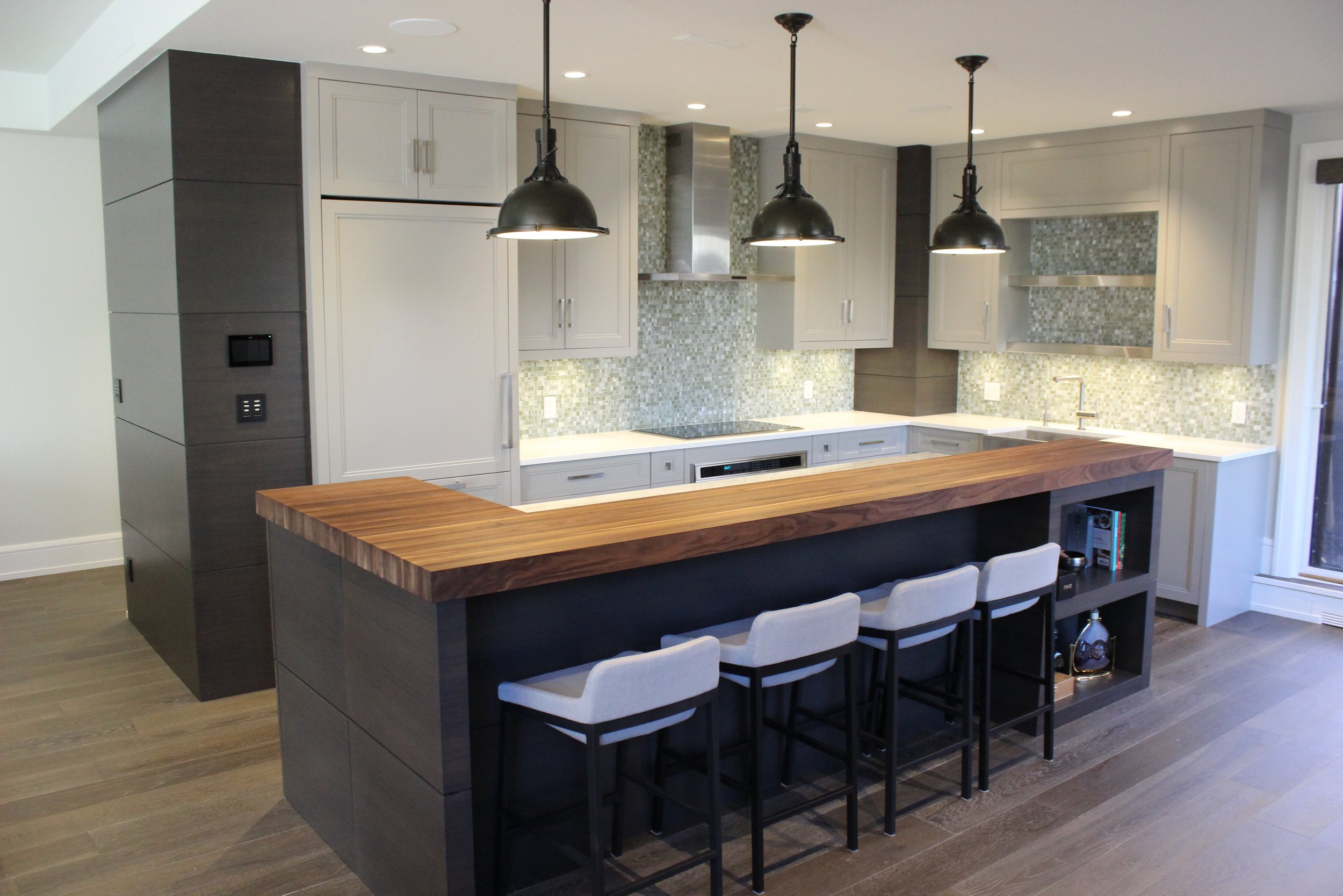 Modern kitchen with white cabinets, mosaic tile backsplash, stainless steel appliances, and a wooden island with seating for four.