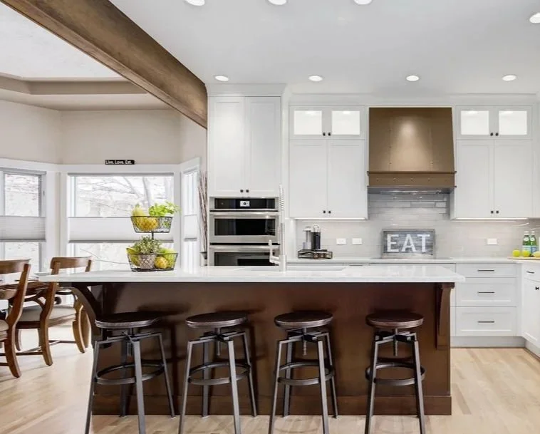 Kitchen with white cabinets, dark wood island, and bronze hood