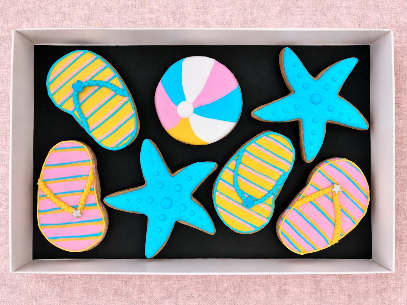Colourful summer theme hand-iced biscuits decorated as flip flops, beach ball and starfish available for UK delivery or decorate your own in an icing workshop, we travel to you