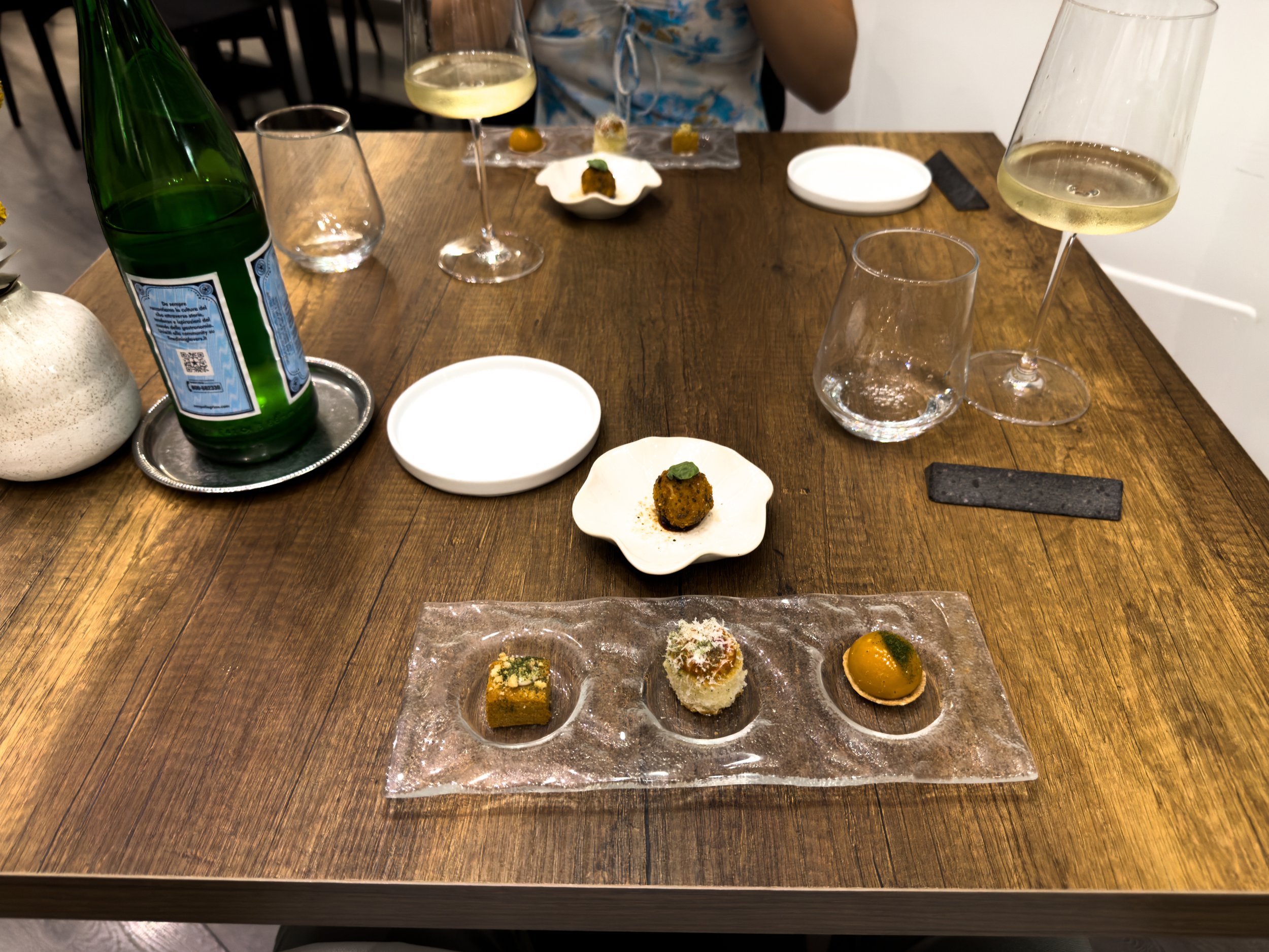 Welcome bites at ALI3I in Palermo, served at the table with white wine before the five-course tasting menu.