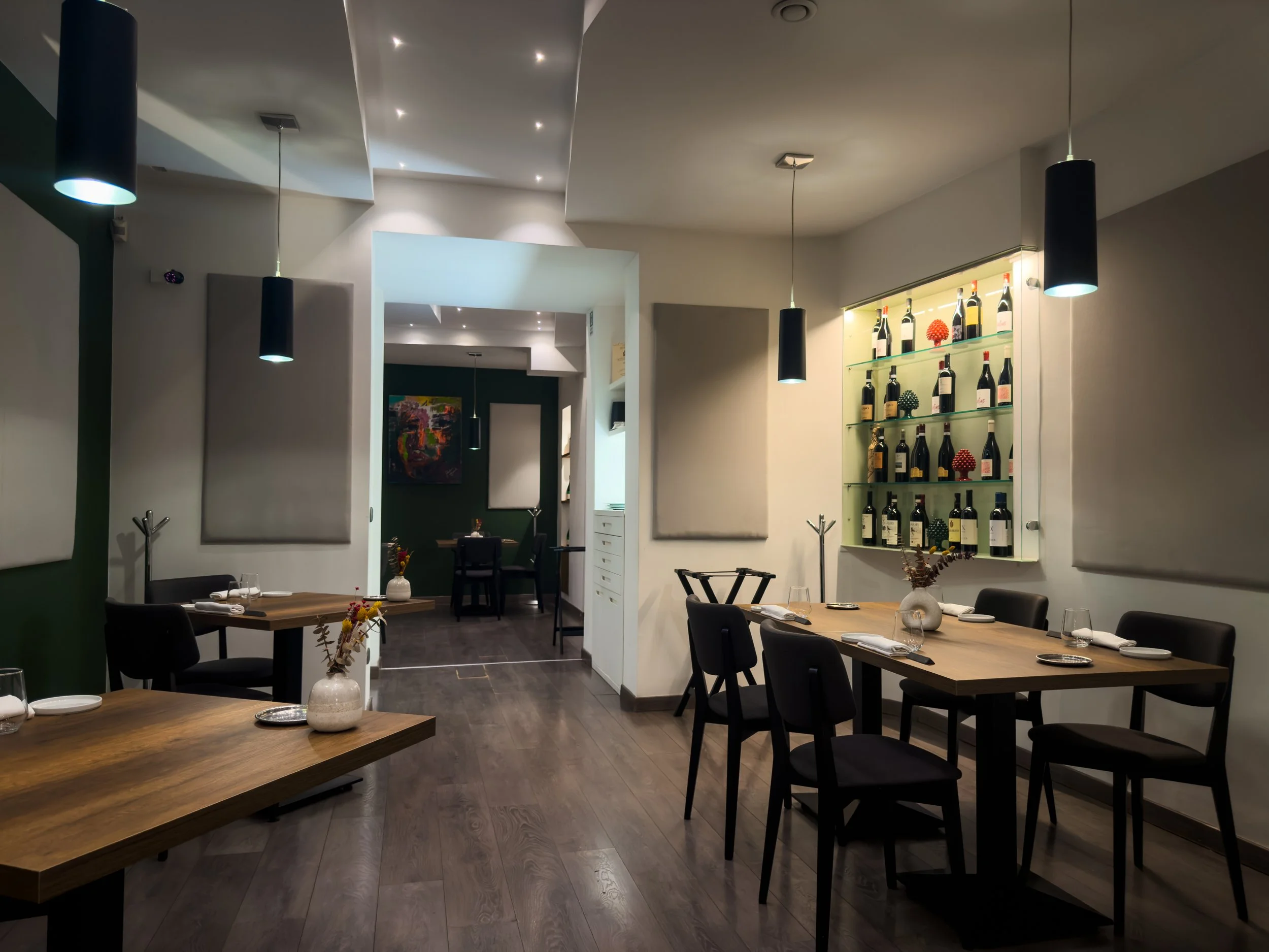 Dining room at ALI3I in Palermo, with contemporary tables, pendant lighting and a large illuminated wine display.