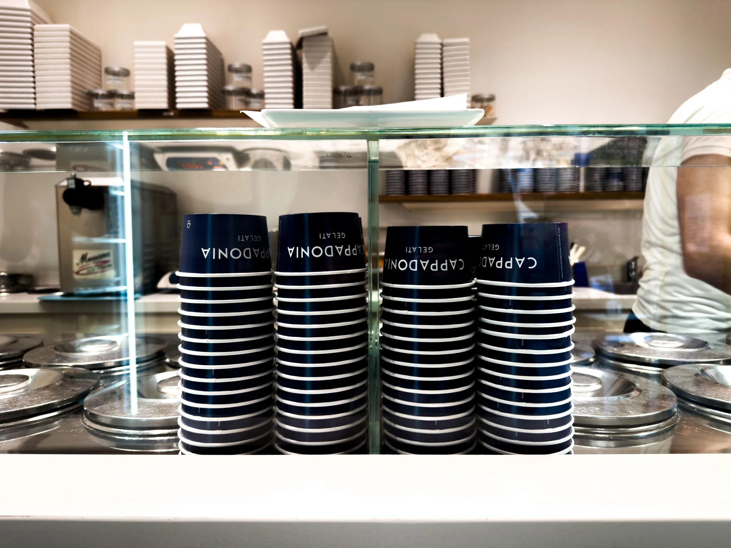 Stacks of blue Cappadonia Gelati cups behind the gelato counter at the Piazzetta Bagnasco shop in Palermo.