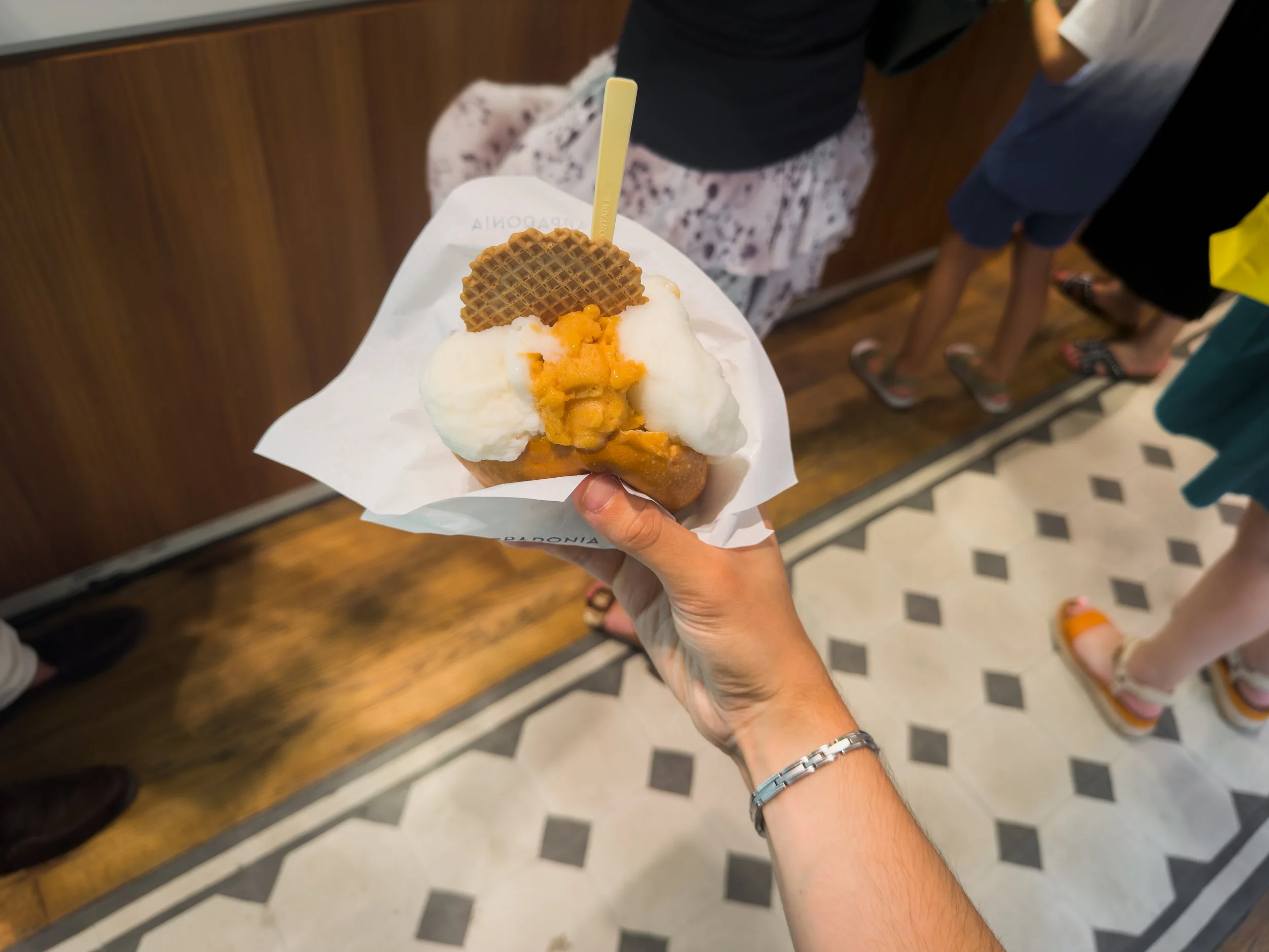 Three-scoop brioche con gelato held above the tiled floor inside Cappadonia Gelati in Palermo.