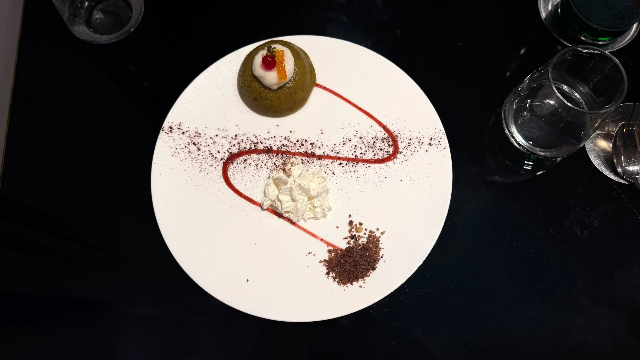 Verde di Sicilia pistachio dessert served as a green dome with cream, red fruit sauce and chocolate crumble at CR21 Palermo.