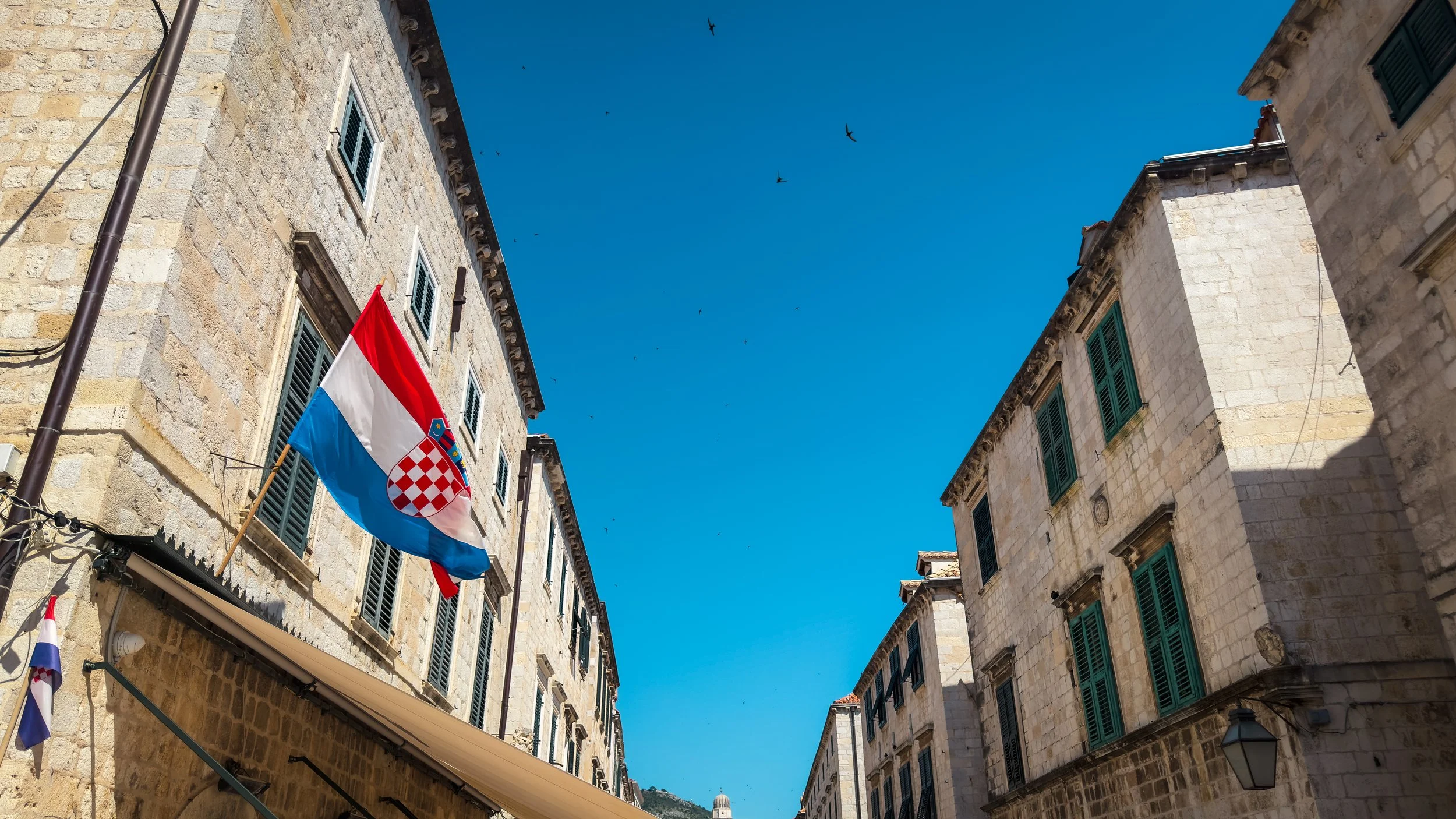 Croatian flag hanging above a stone street in Dubrovnik Old Town.