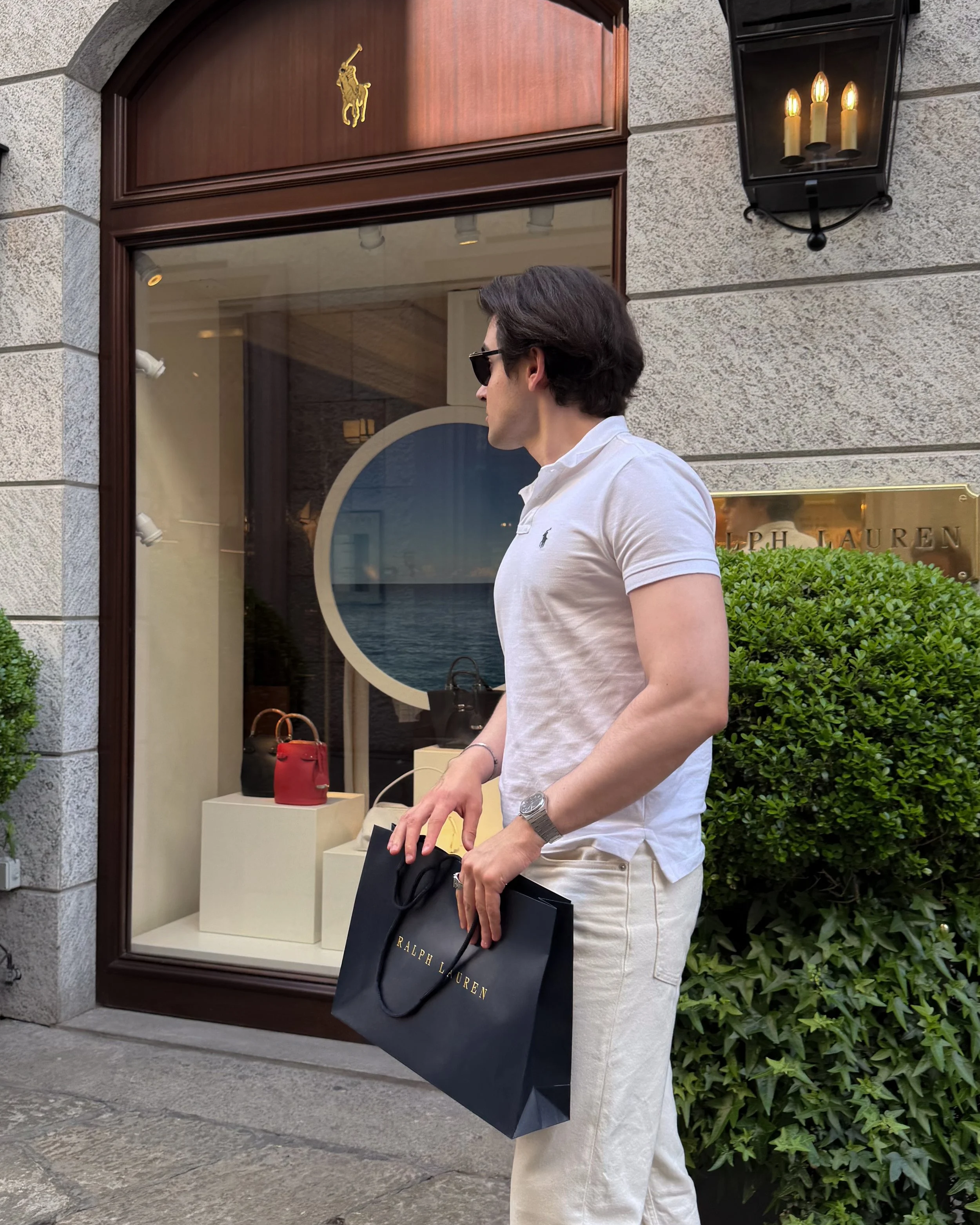 Man standing outside Ralph Lauren Milano holding a shopping bag before visiting Ralph’s Bar.