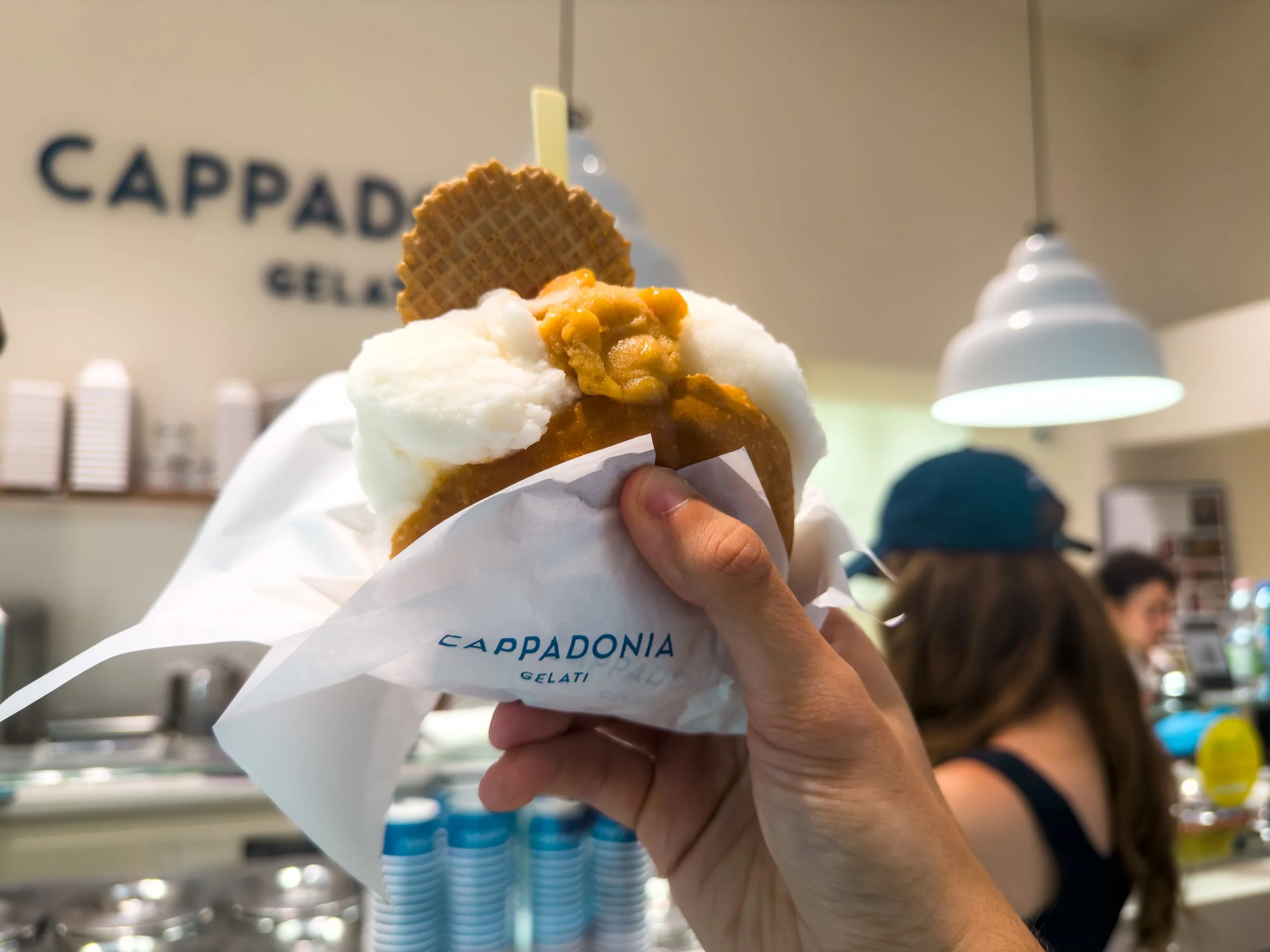 Brioche filled with three scoops of gelato held in front of the Cappadonia Gelati counter in Palermo.
