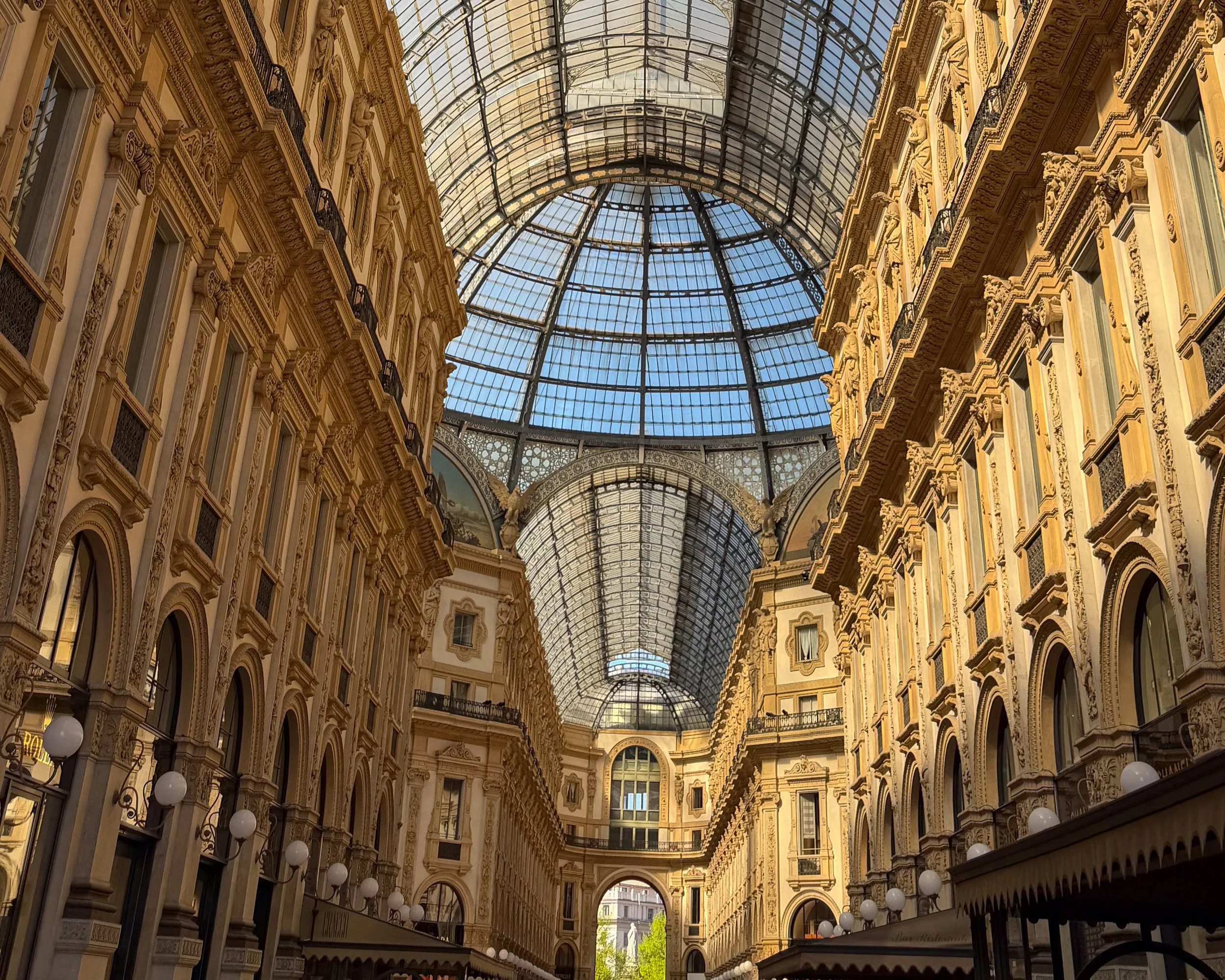 Galleria Vittorio Emanuele II in Milan with ornate historic architecture and a glass roof.