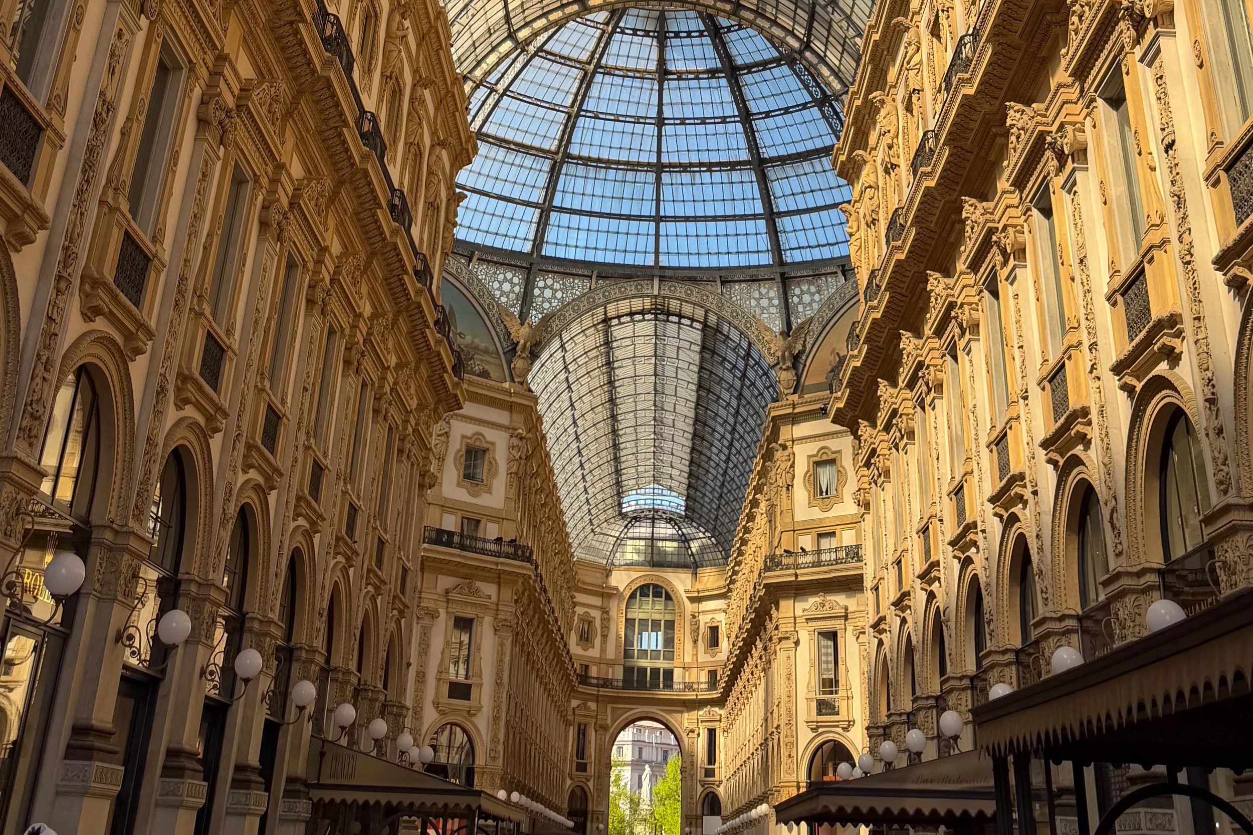 Interior of Galleria Vittorio Emanuele II in Milan with ornate architecture and a glass-domed roof.