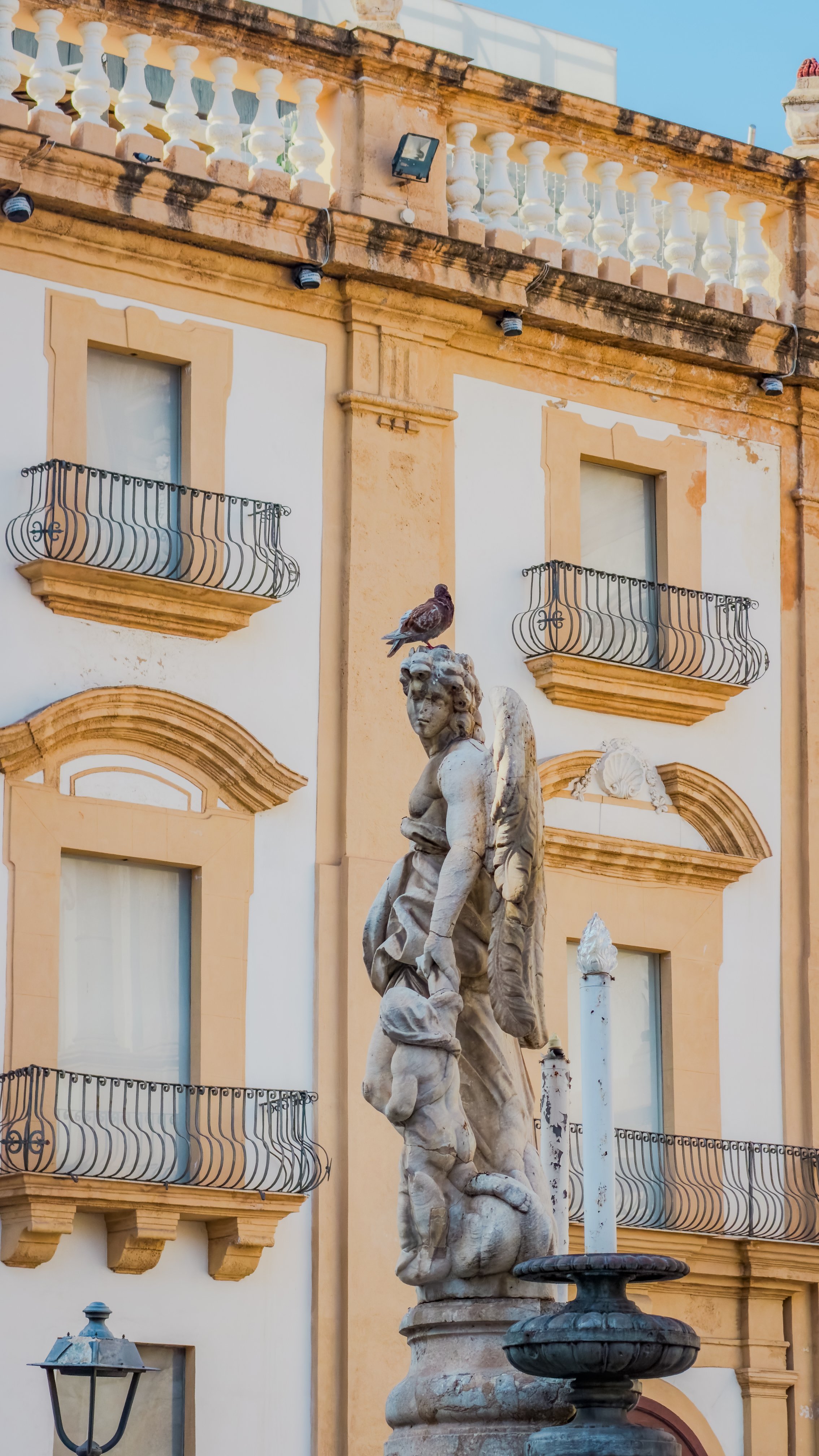 Marble angel sculpture with a pigeon on its head in Piazza San Domenico, Palermo.