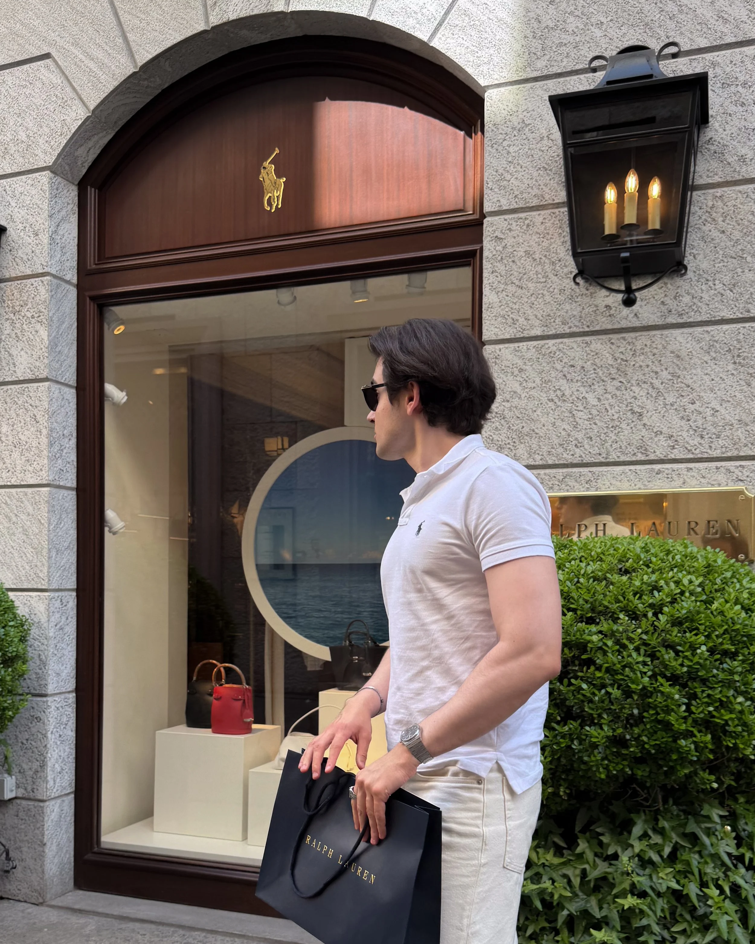 Man holding a Ralph Lauren shopping bag outside Ralph Lauren Milano in the Milan fashion district.